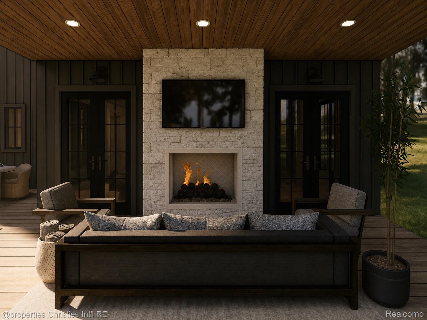 Covered patio with a stone fireplace, mounted television, and dark outdoor seating.