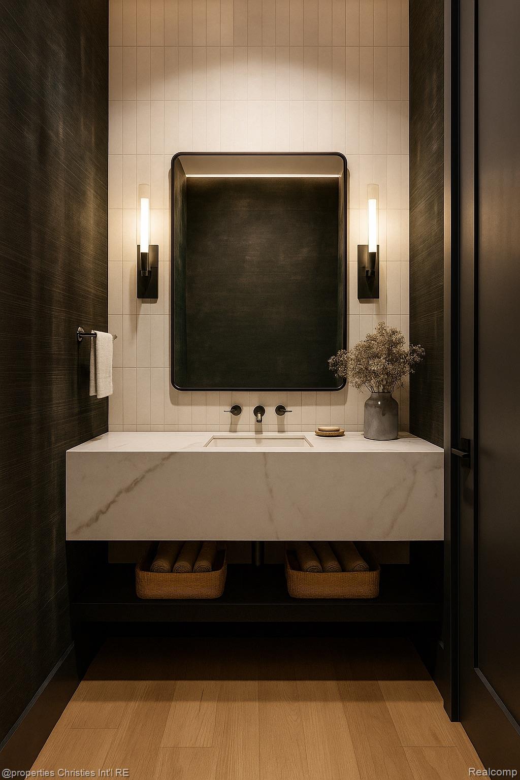Bathroom vanity with a marble countertop, dark-framed mirror, and paired wall sconces.