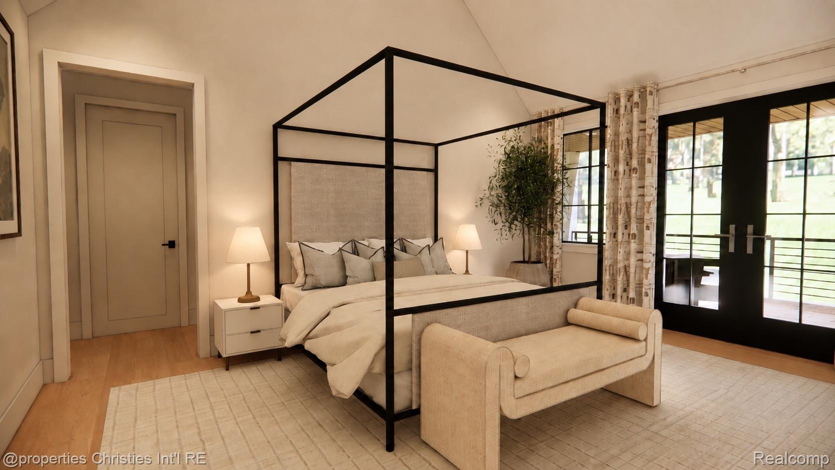 Staged bedroom with a black canopy bed, cream bedding, and glass doors overlooking a lawn.