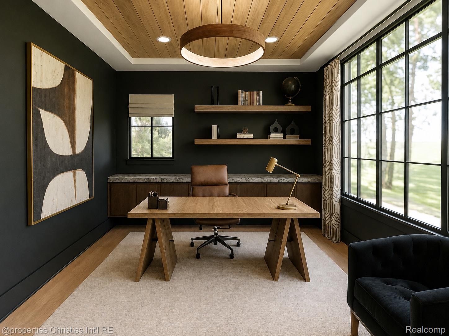 Home office with a broad wood desk, charcoal walls, and tall black-framed windows.