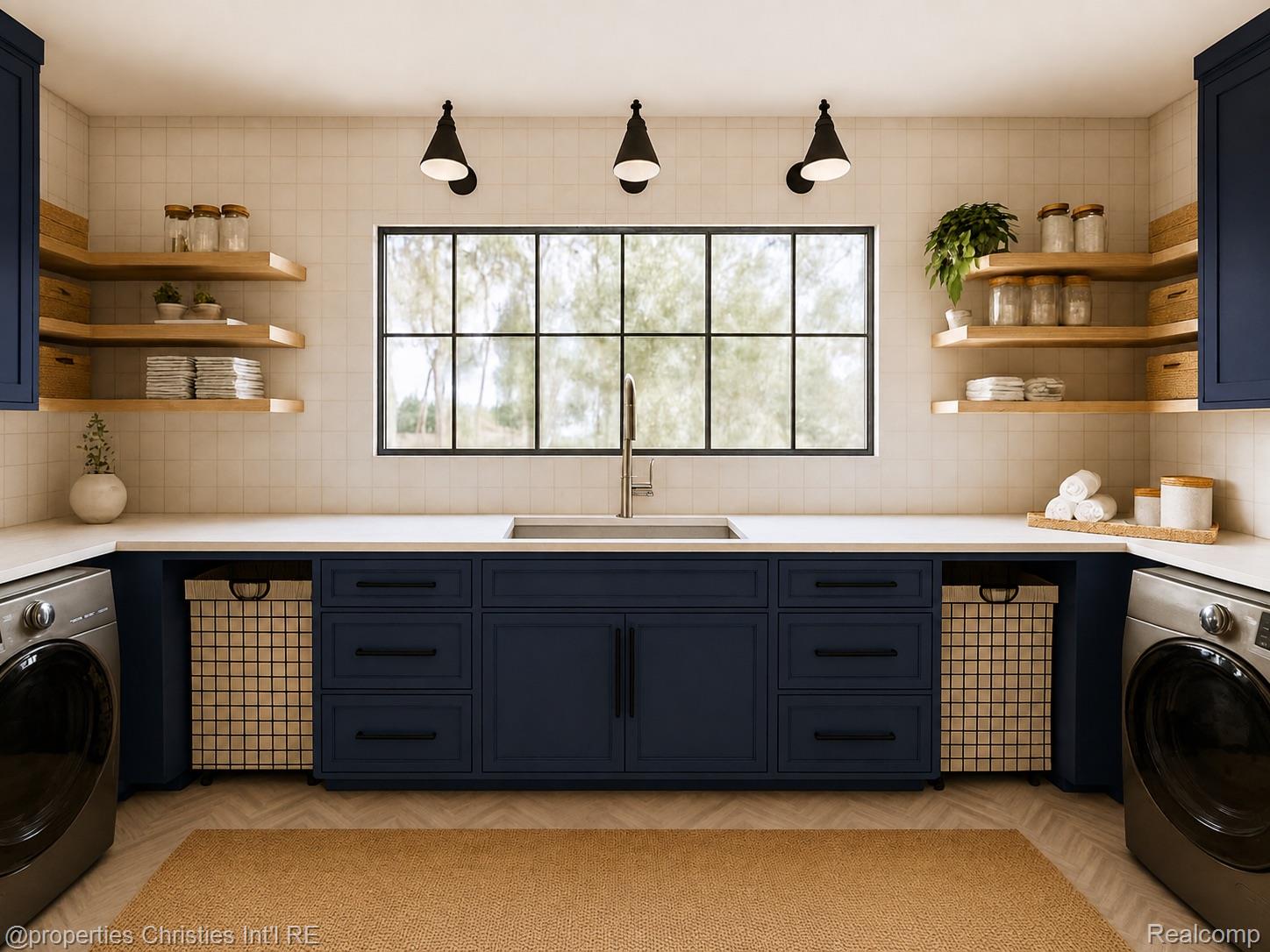 Laundry room with navy cabinetry, a wide sink beneath a window, and front-loading washers.