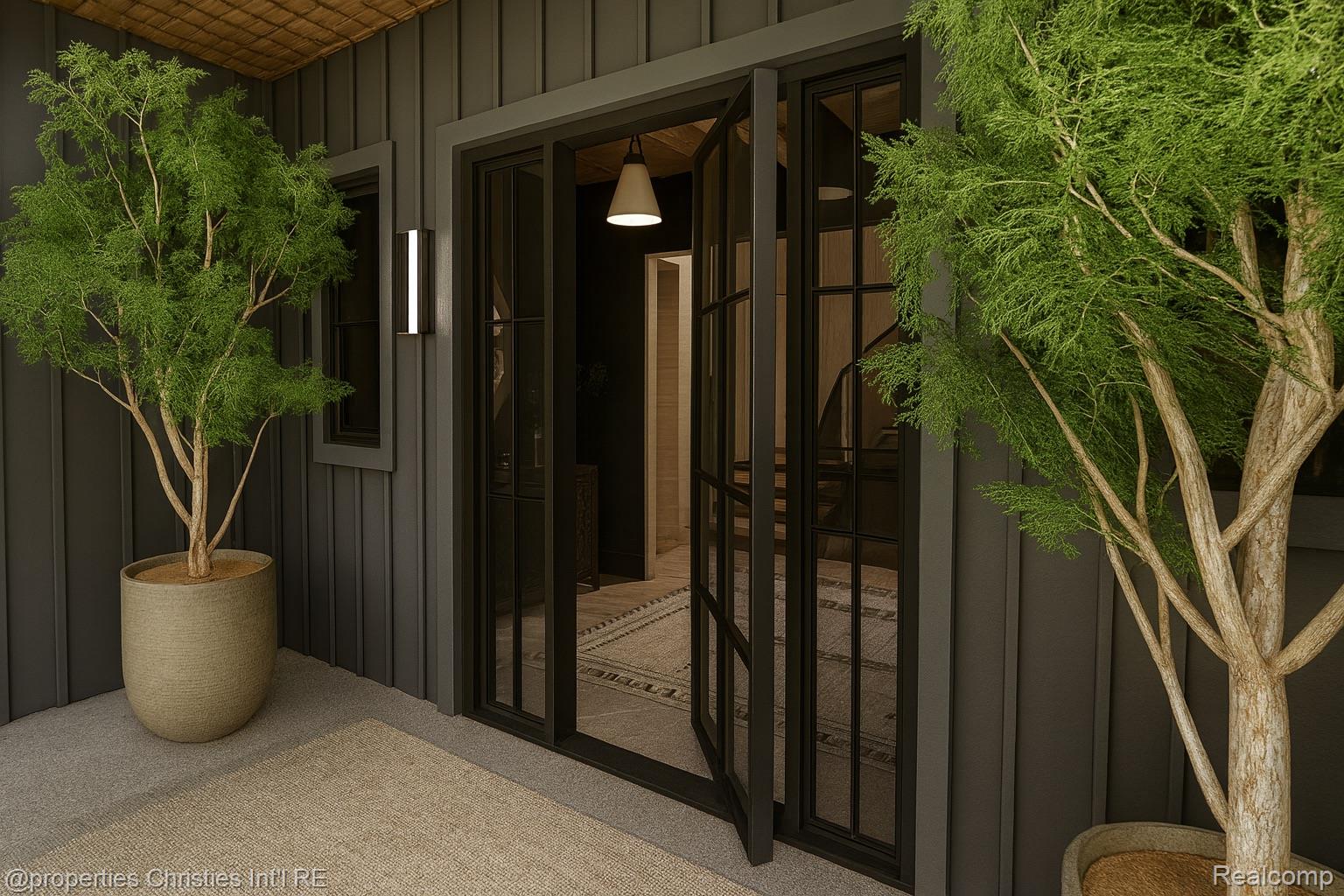 Covered home entrance with black-framed glass doors and potted trees on either side.