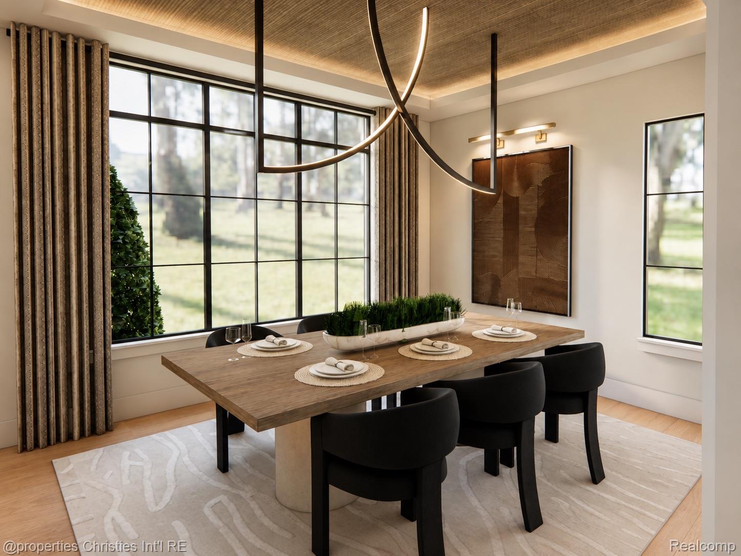 Dining room with a wooden table, black chairs, sculptural chandelier, and large windows overlooking a lawn.