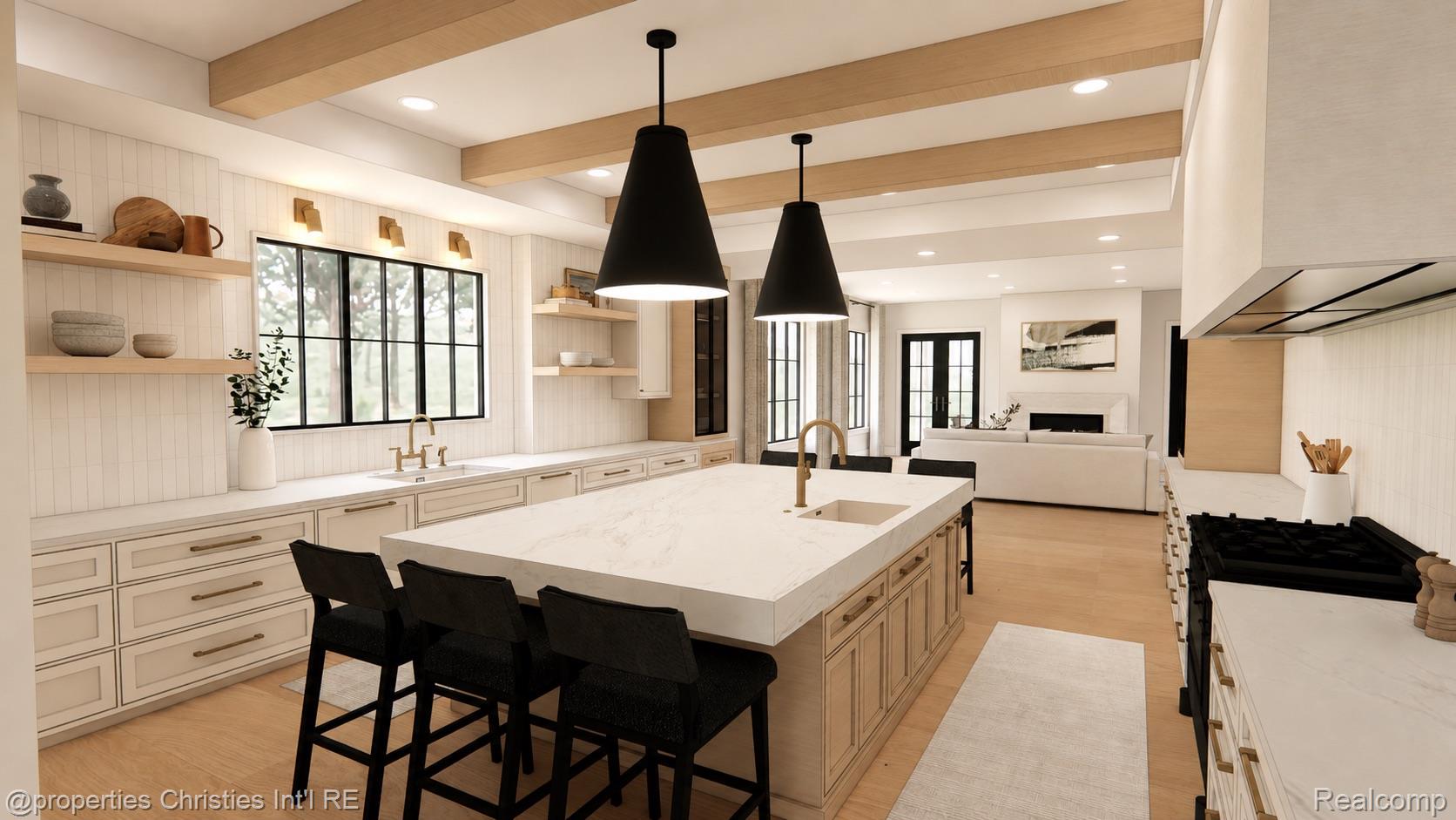 Open-plan kitchen with a large white island, black pendant lights, and pale wood ceiling beams.