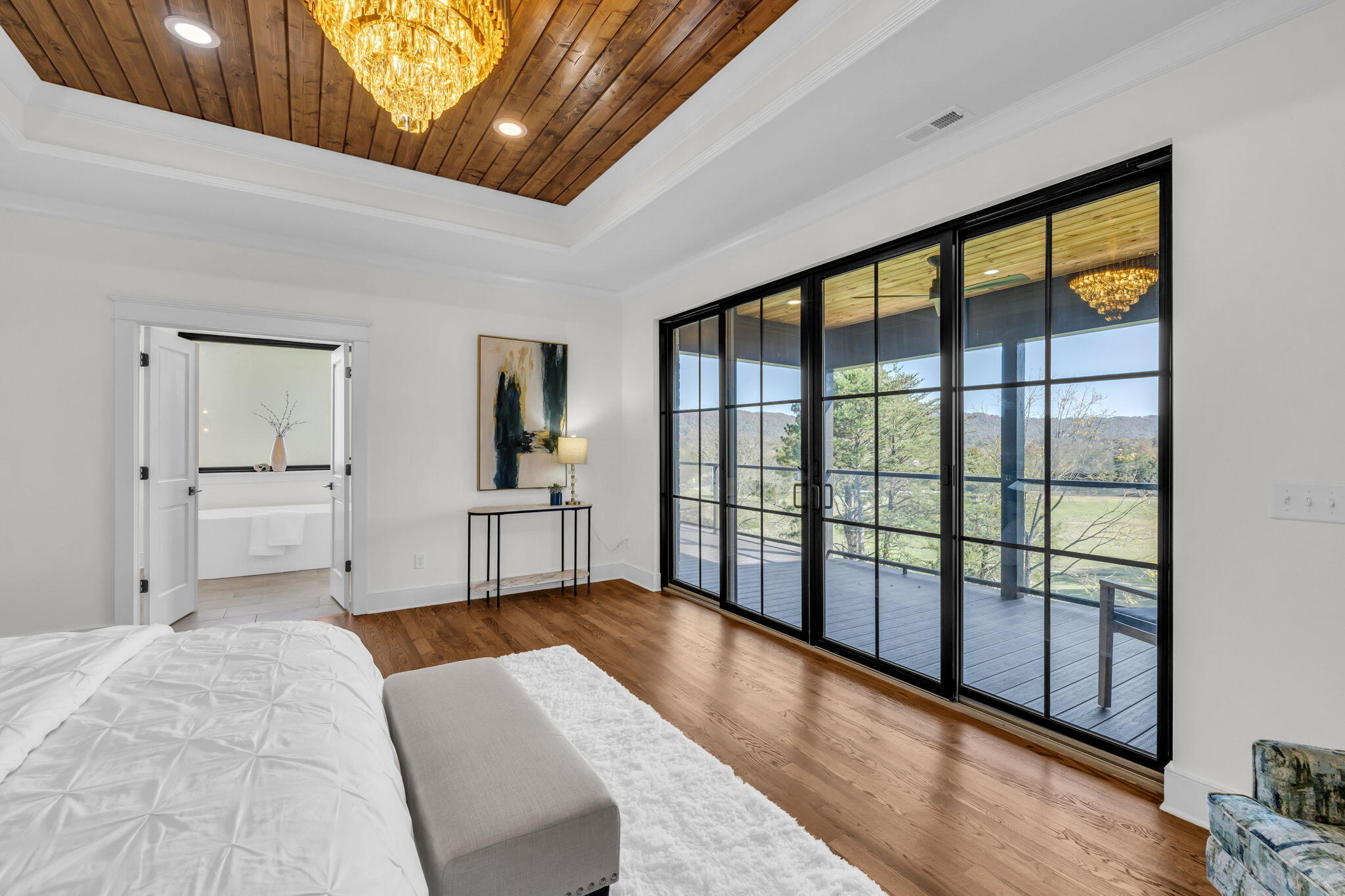 Bedroom with wood-plank ceiling, glass doors to a deck, and an en suite soaking tub.