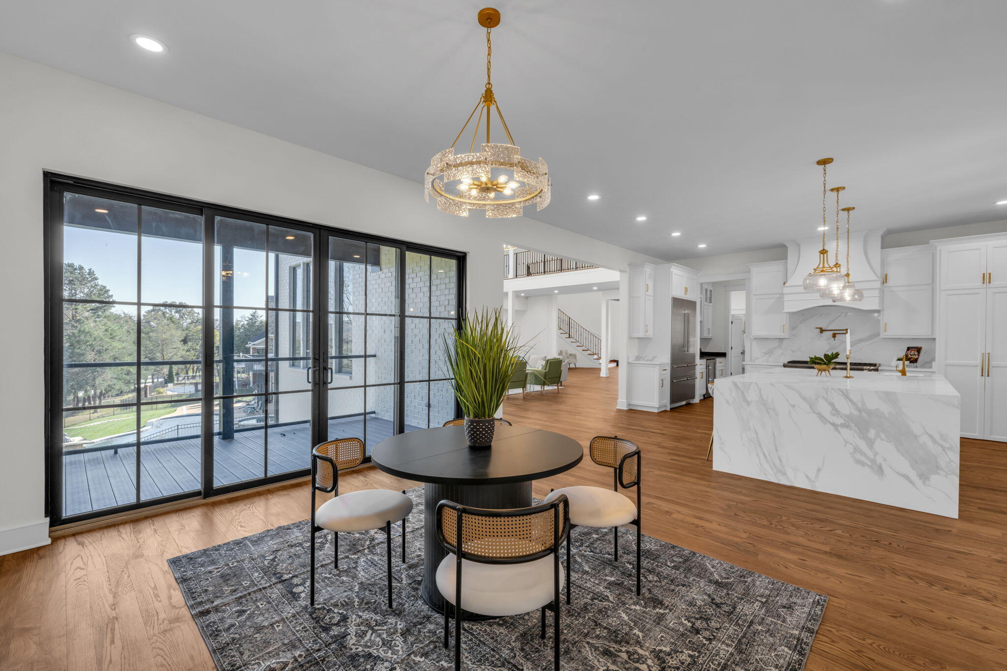 Open-plan kitchen and dining area with a marble island, round table, and large black-framed glass doors.