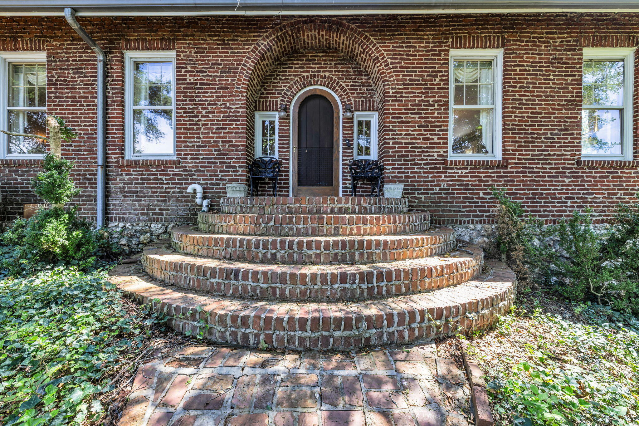 Red brick home entrance with an arched doorway and broad curved brick steps.