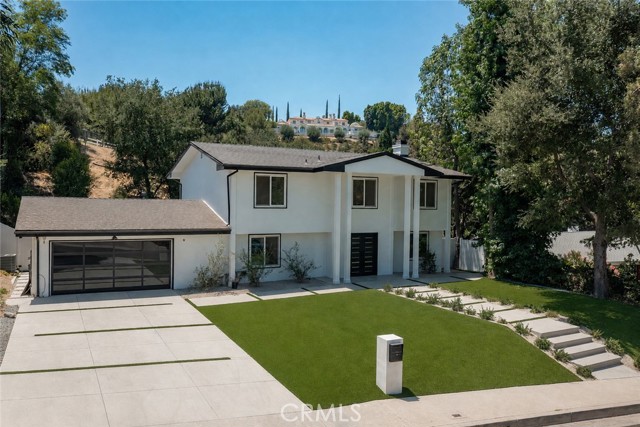 Modern white two-story house with an attached garage, landscaped lawn, and broad concrete driveway.