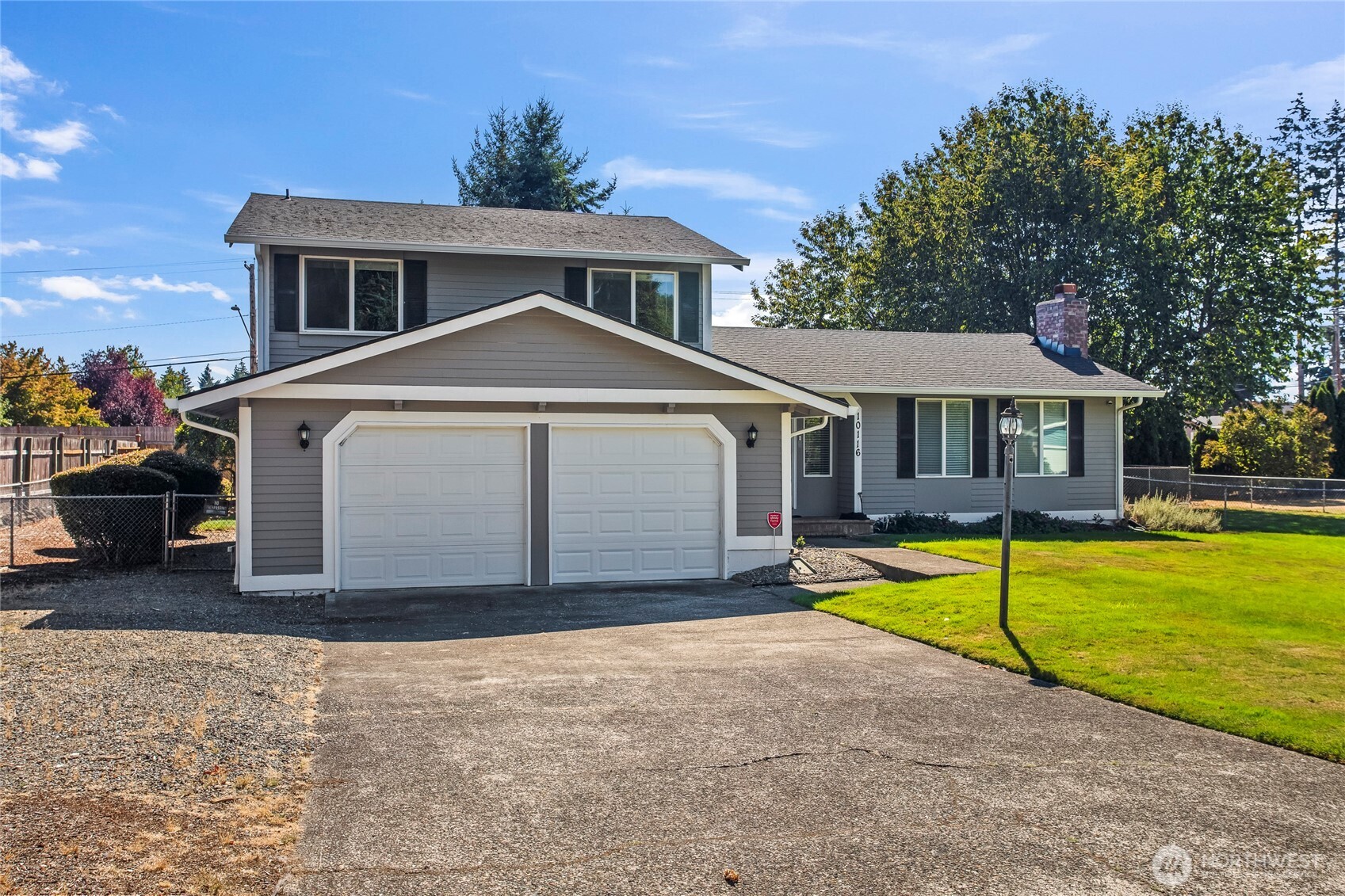 Gray two-story house with a gabled entry, two-car garage, and broad driveway.