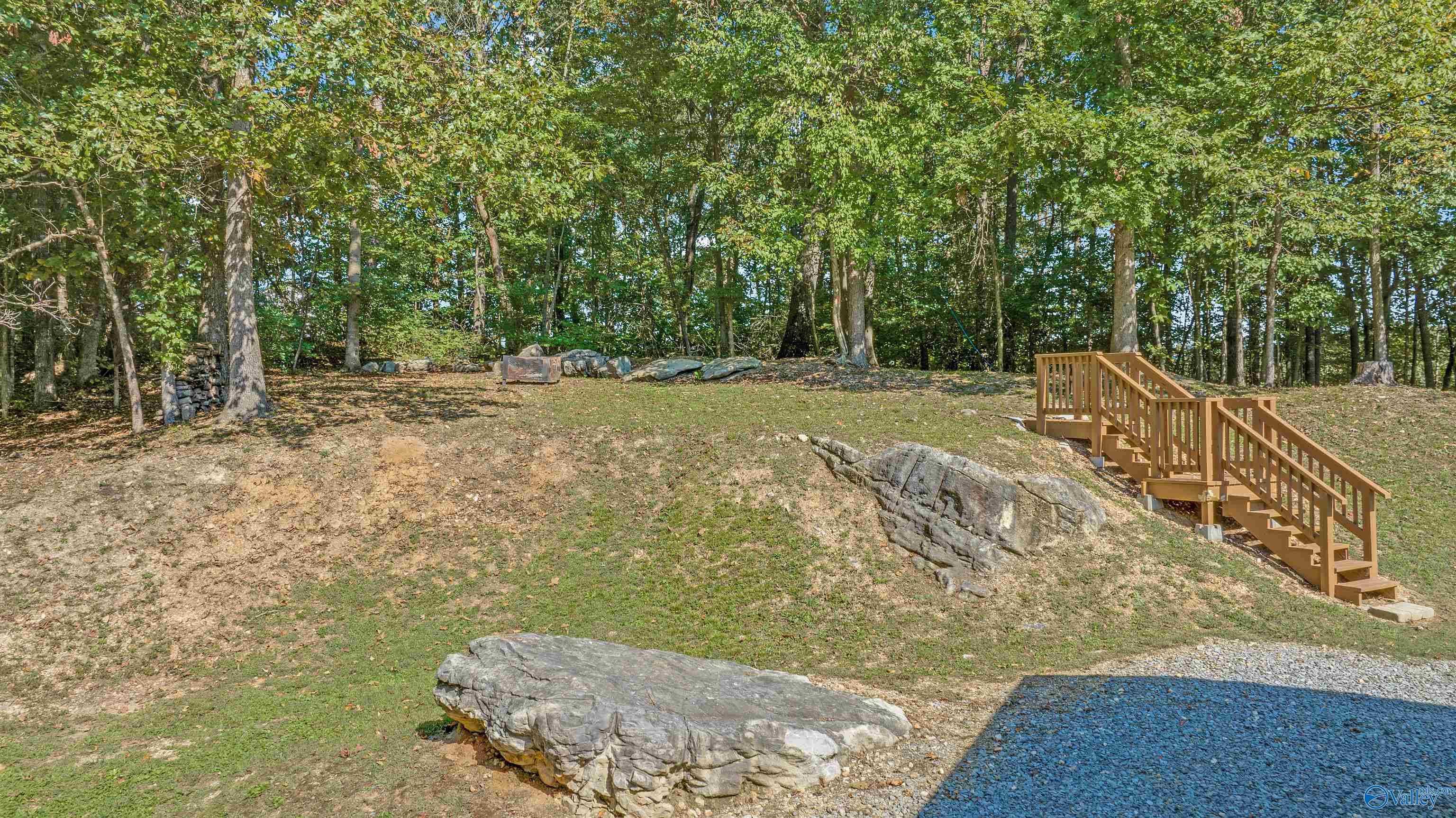 Wooded yard with exposed rock outcrops and a long wooden staircase.