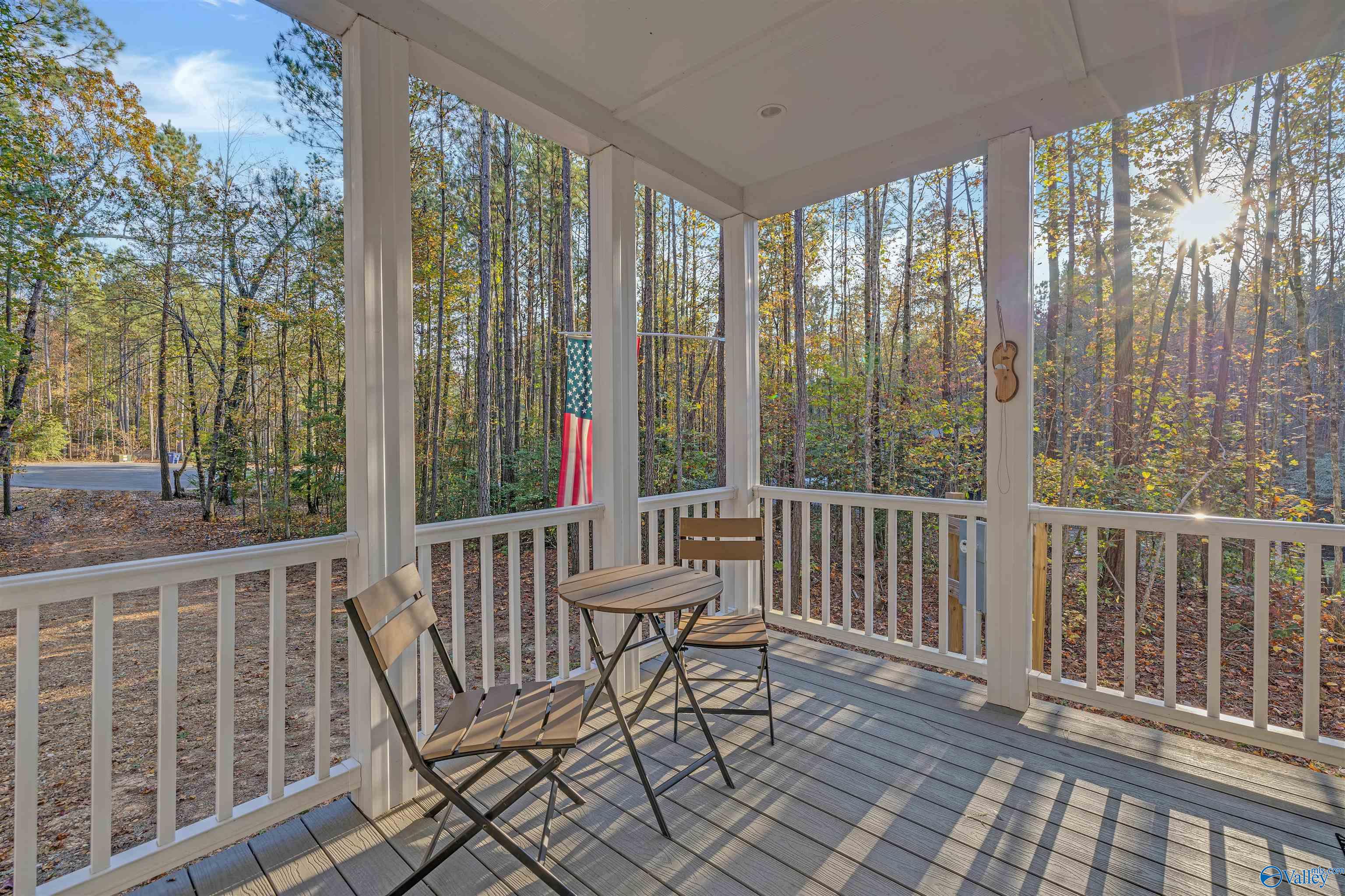 Covered porch with a round table and chairs overlooking autumn woods.