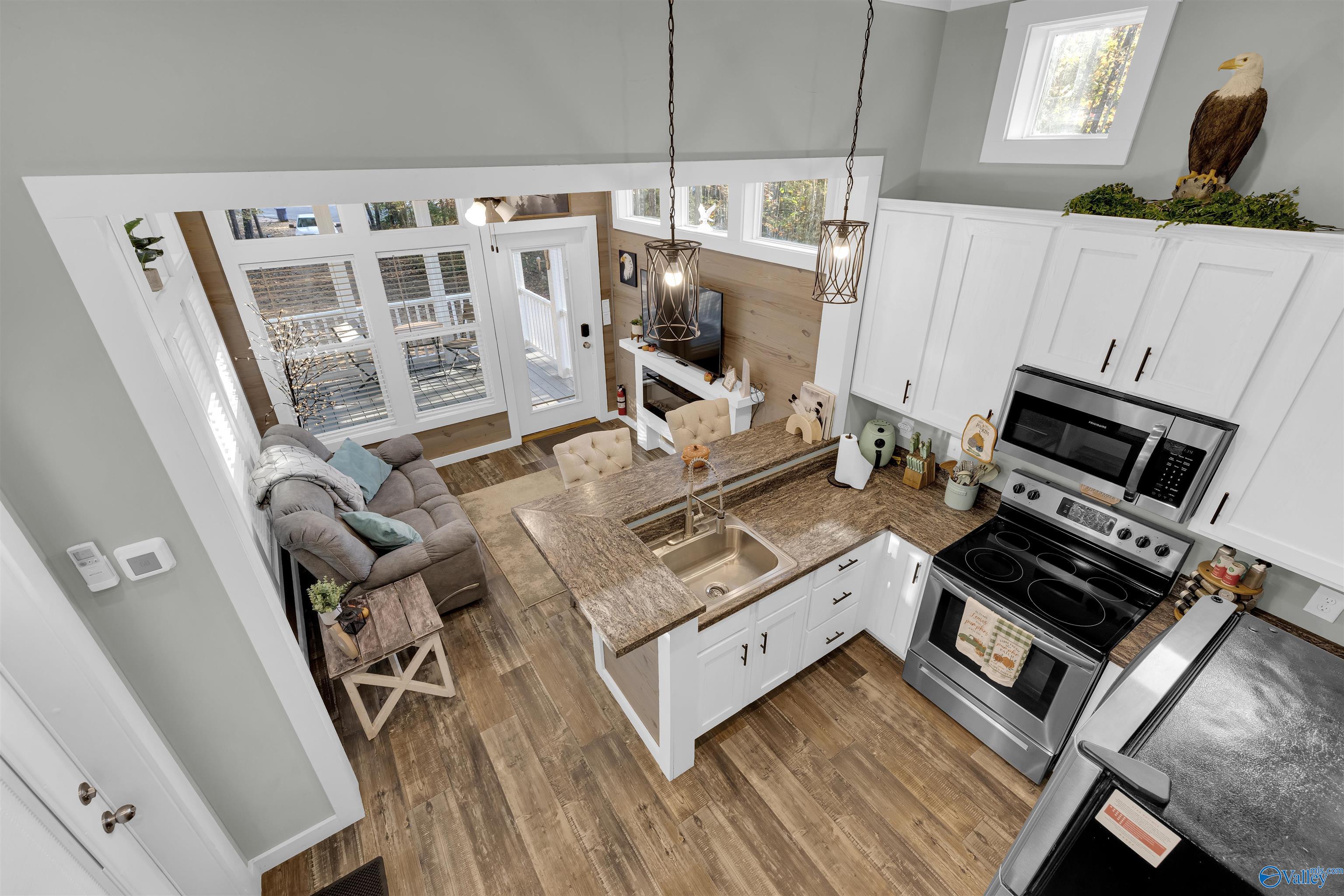 Open-plan kitchen and living room with a large stone island and tall windows.