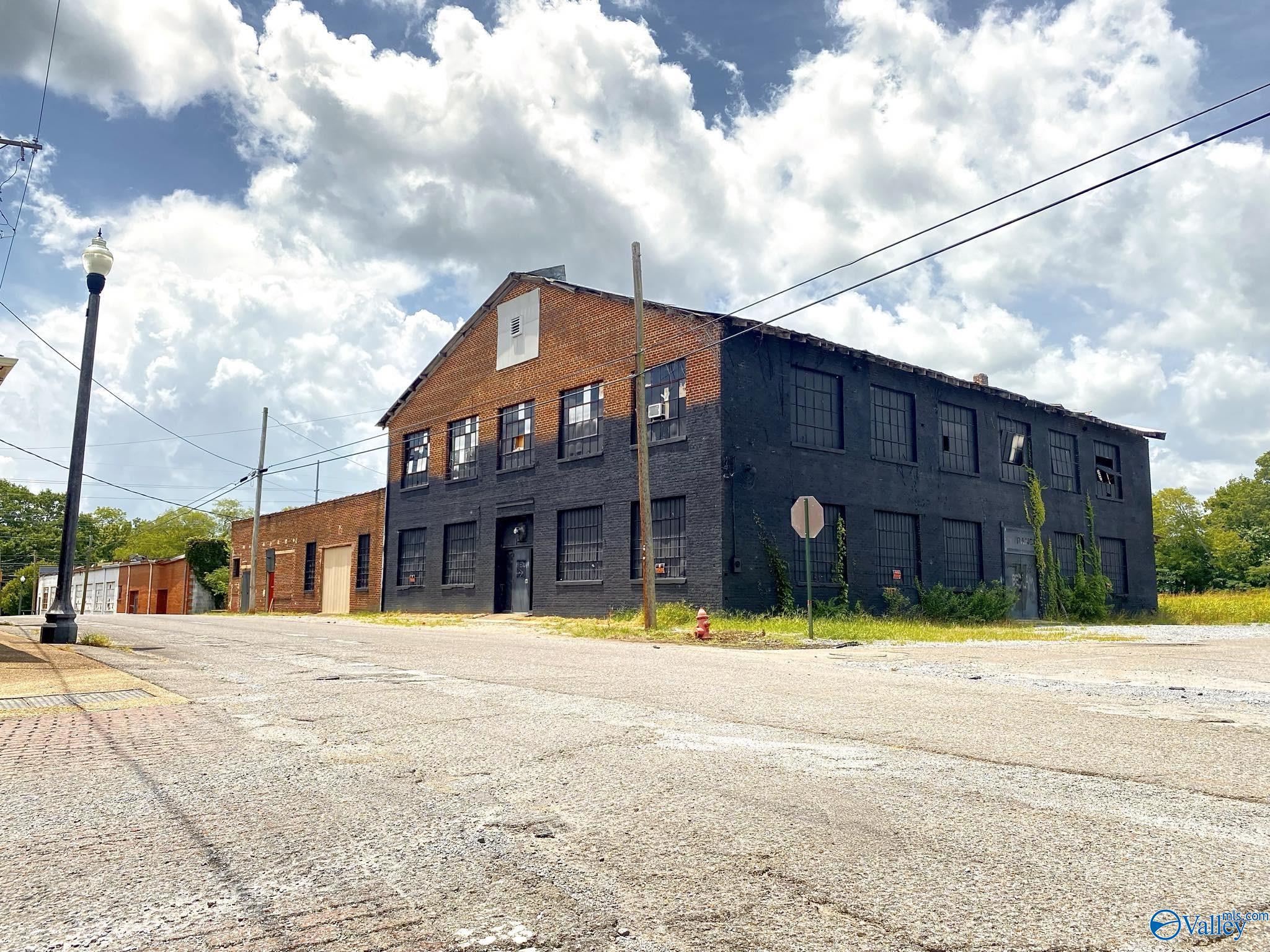 Two-story brick commercial building with a dark facade and rows of tall industrial windows.