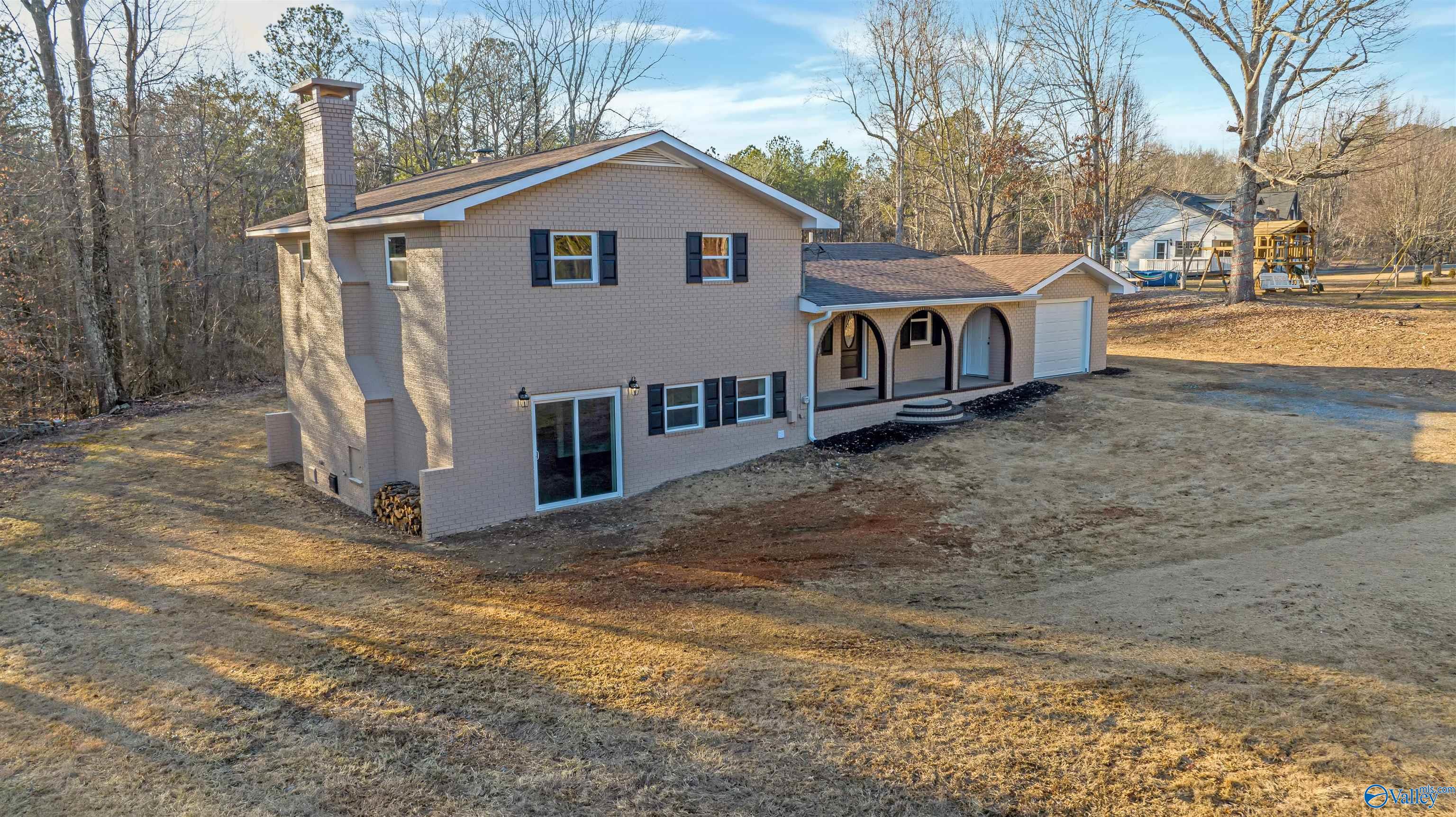 Two-story brick house with an arched porch, attached garage, and broad lawn.