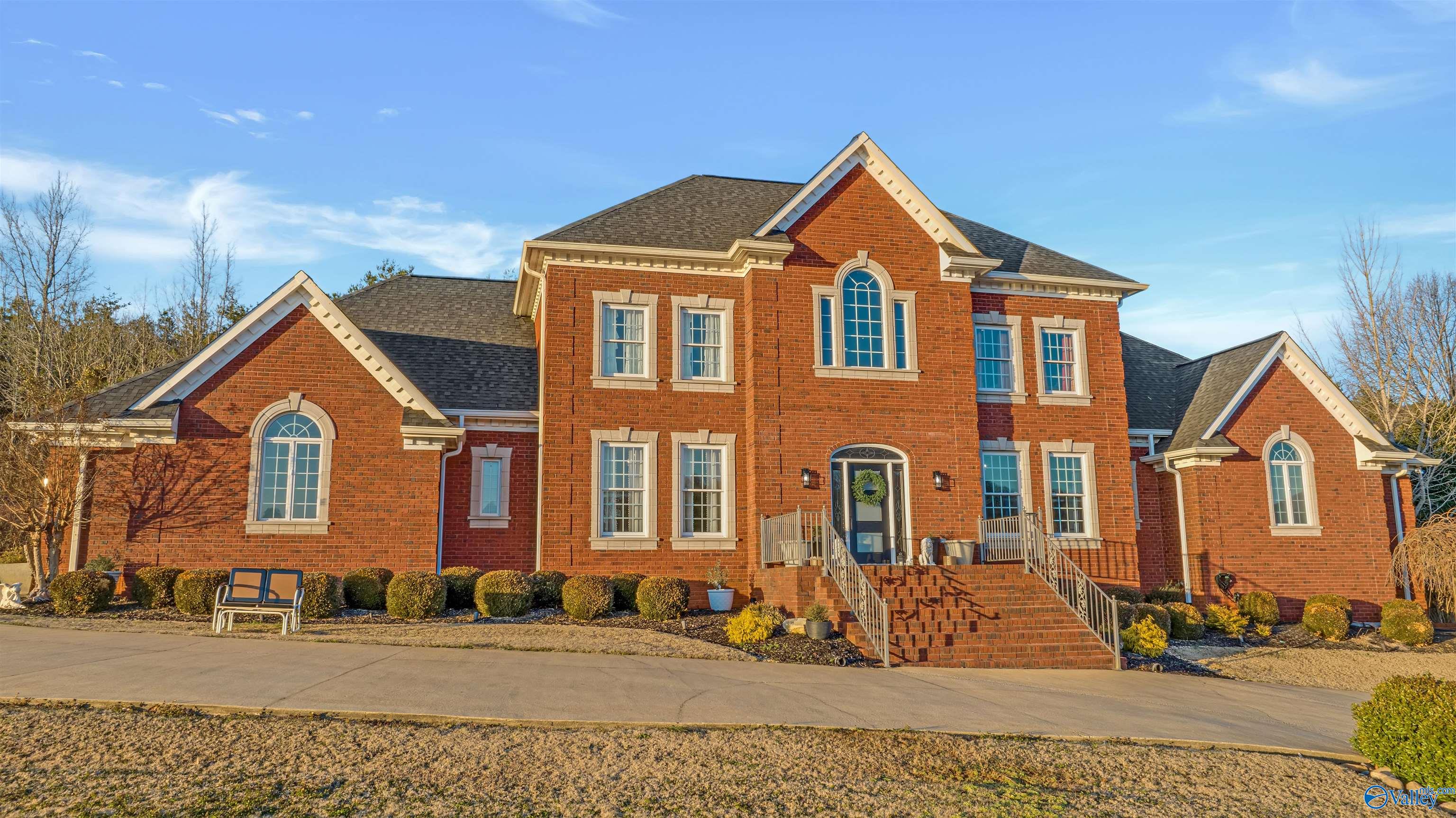 Two-story red-brick home with multiple gables, cream trim, and a raised front entry.