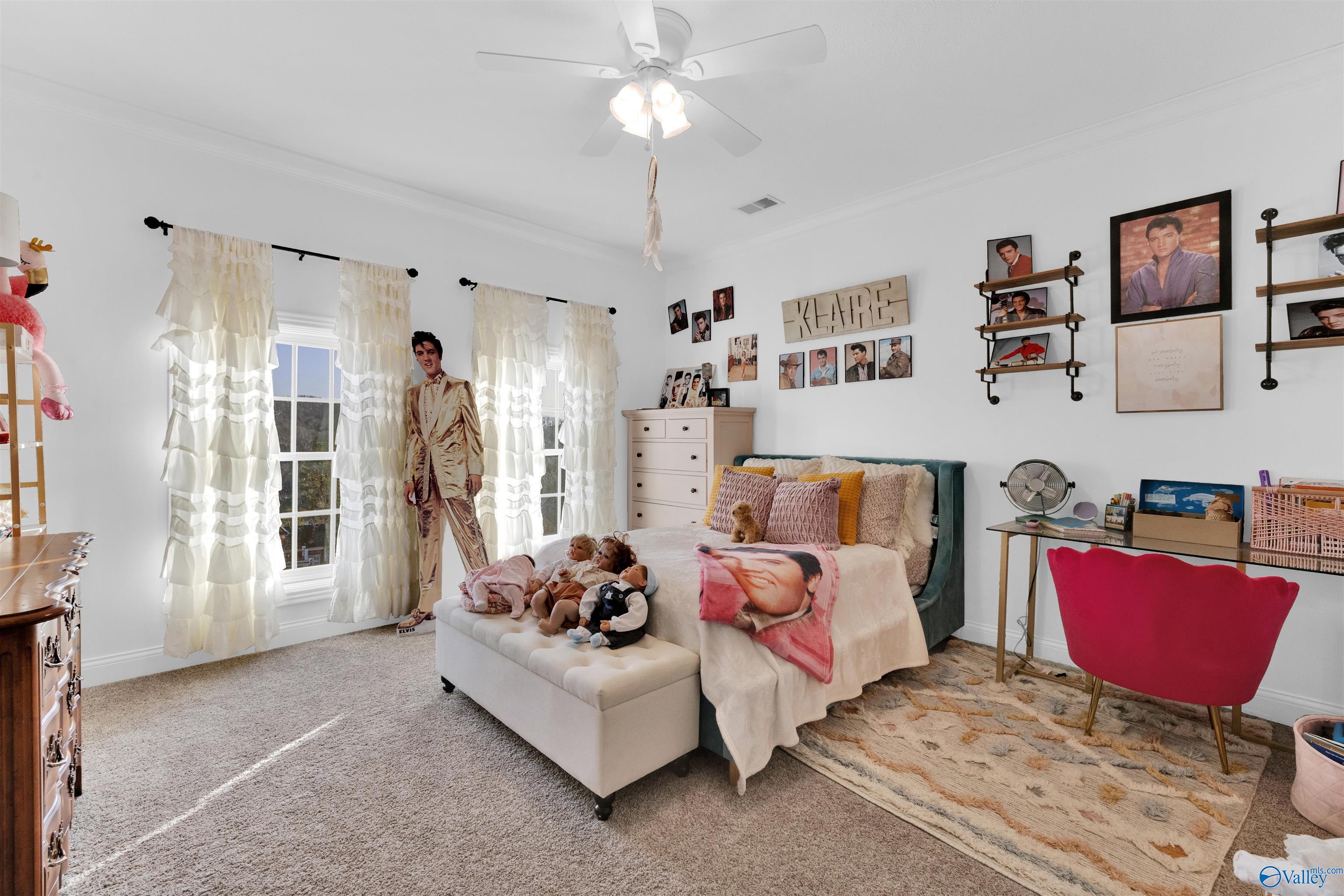 Bedroom with an Elvis Presley theme, including a life-size cutout, portrait gallery, and printed bedding.
