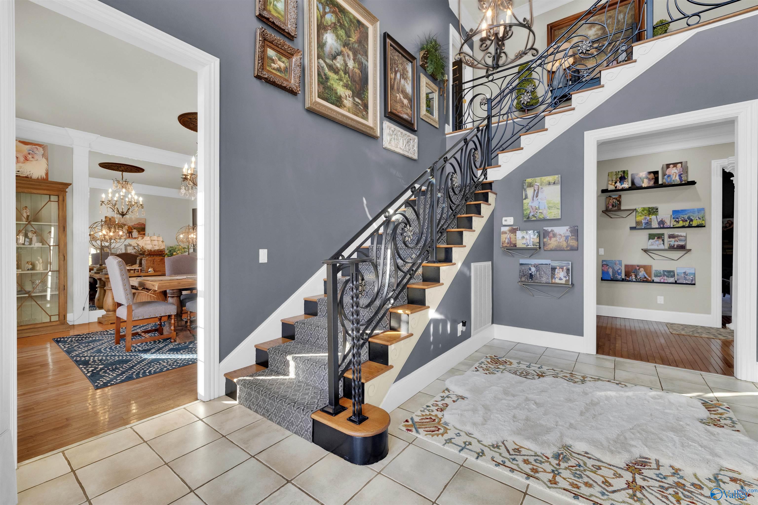 Foyer with an ornate curved staircase, tiled floor, and open doorways to adjoining rooms.