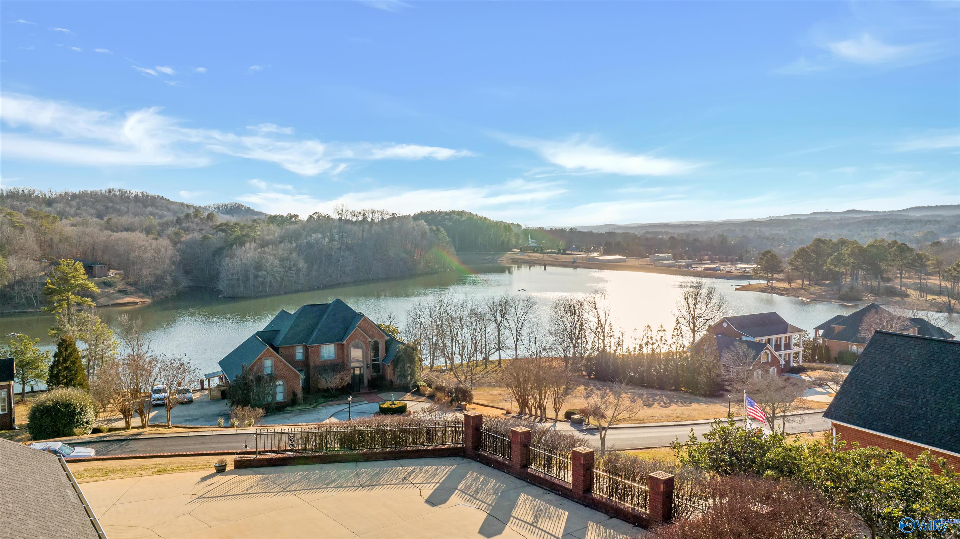 Lake view from a fenced patio, with nearby homes and wooded hills beyond.