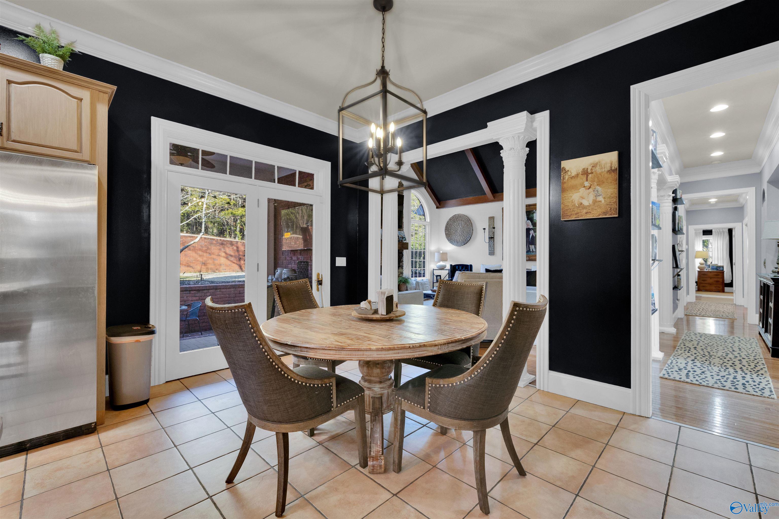 Dining room with round wood table, upholstered chairs, black walls, and glass patio doors.