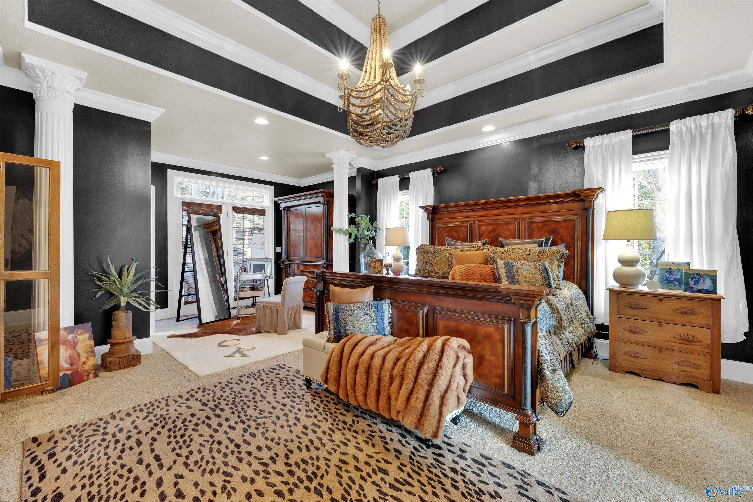 Bedroom with a carved wooden bed, charcoal walls, white columns, and a dramatic coffered ceiling.