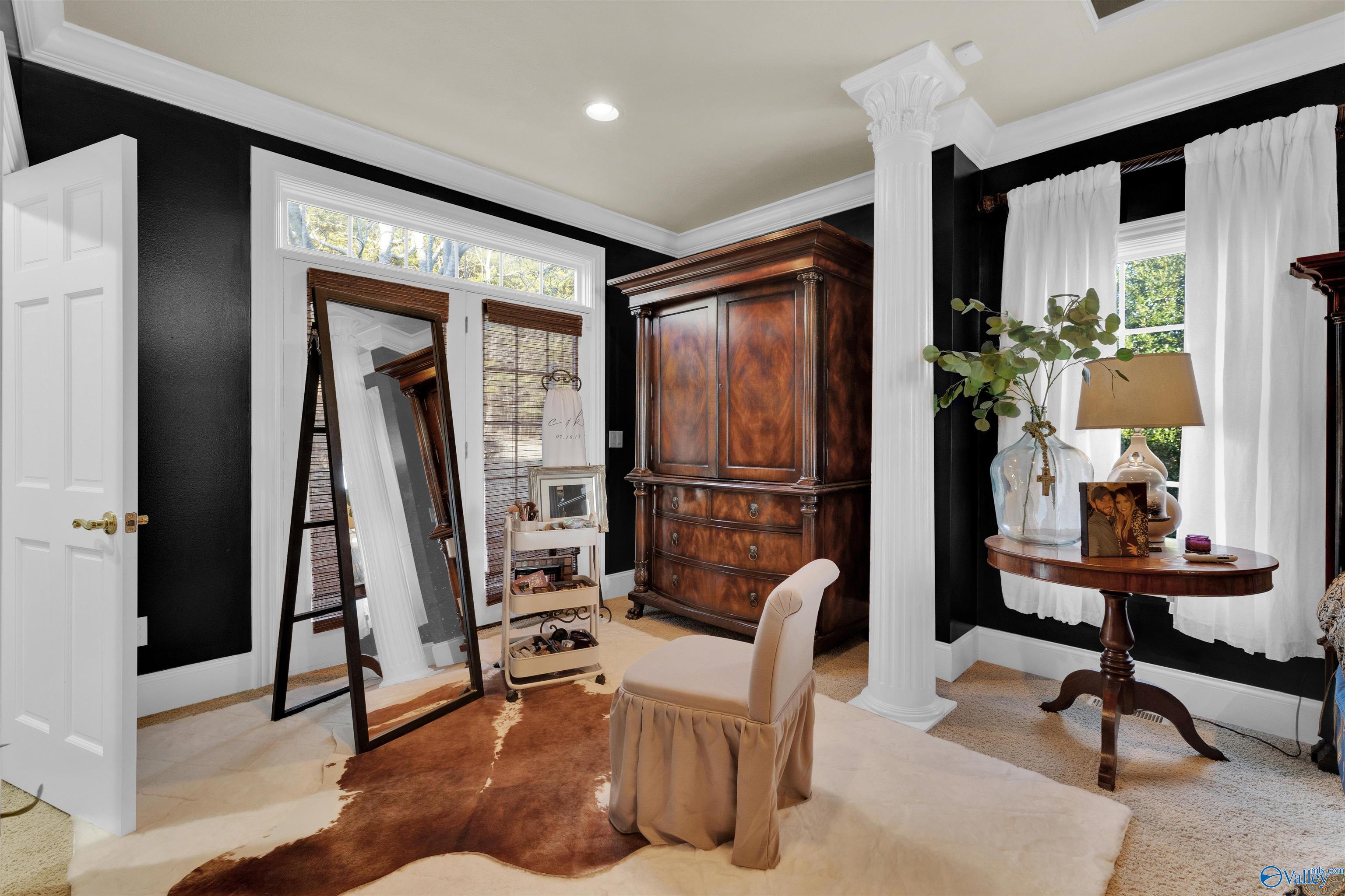 Dressing room with an ornate wooden armoire, full-length mirror, and white column against black walls.