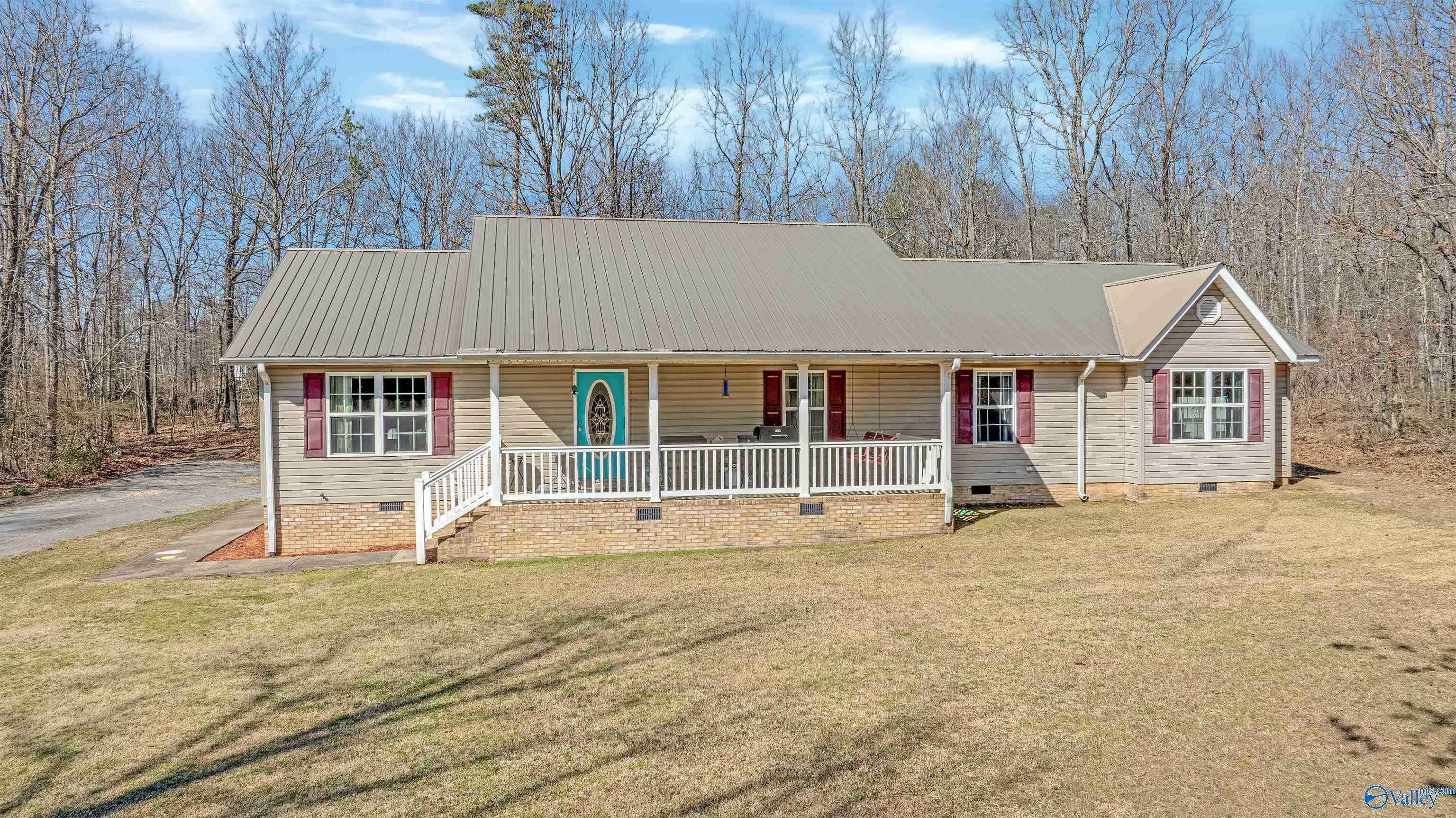 Single-story home with a metal roof, covered porch, and turquoise front door.