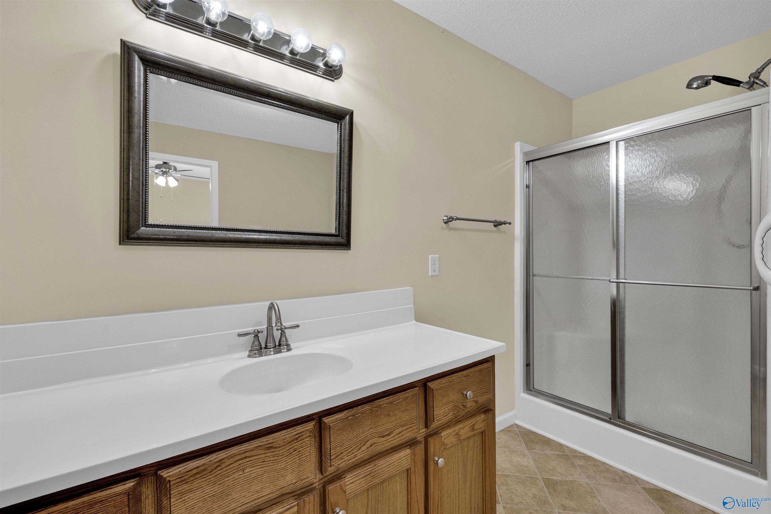 Bathroom with a wood vanity, white sink countertop, and sliding frosted-glass shower doors.