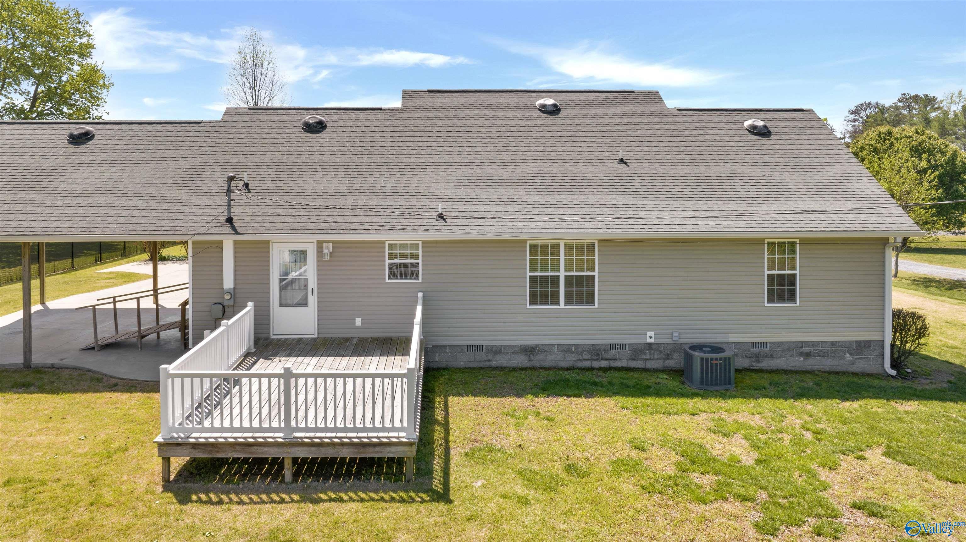 Rear of a gray-sided home with a raised white-railed deck and covered patio.