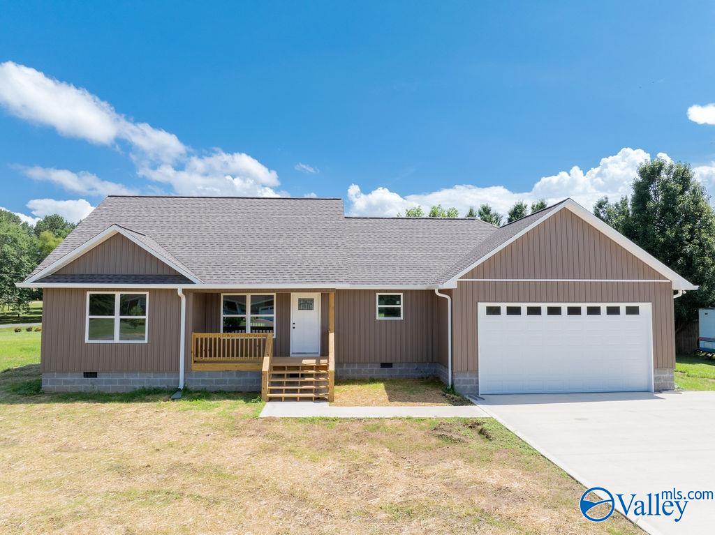 Single-story brown home with a covered porch, white garage door, and concrete driveway.