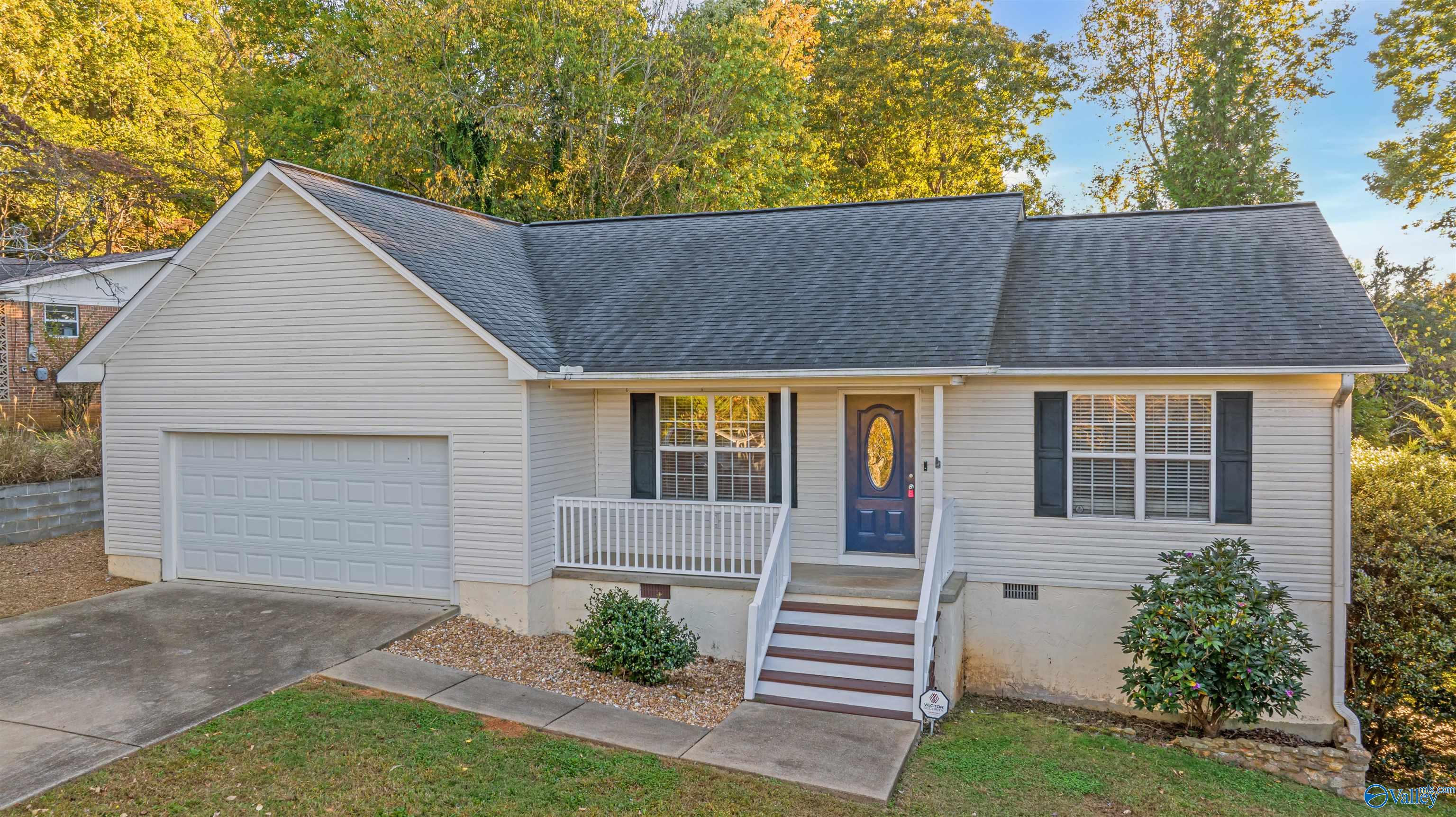 Single-story gray house with an attached garage, blue front door, and white-railed porch steps.
