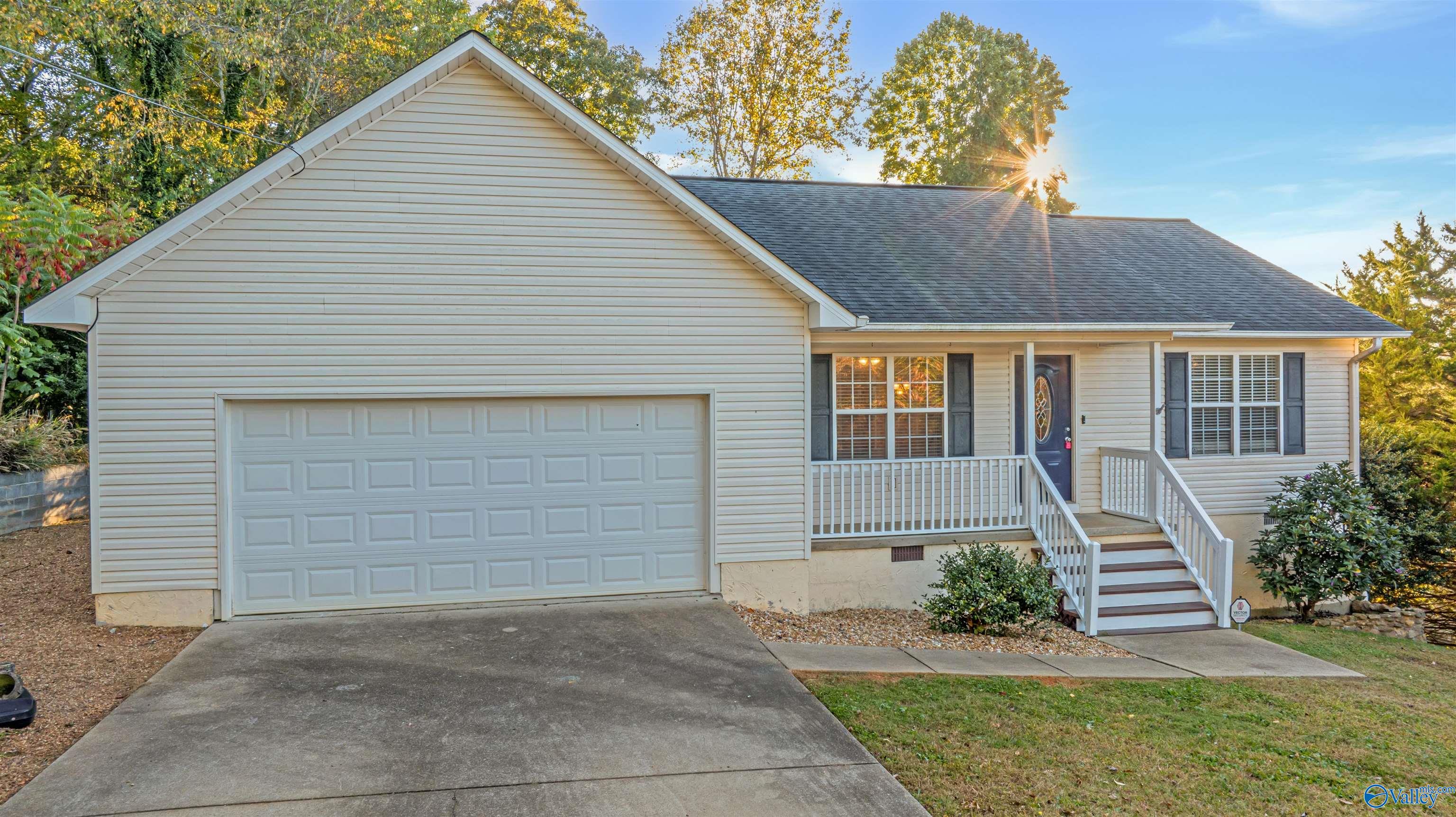 Home exterior with an attached two-car garage and raised porch in golden-hour light.