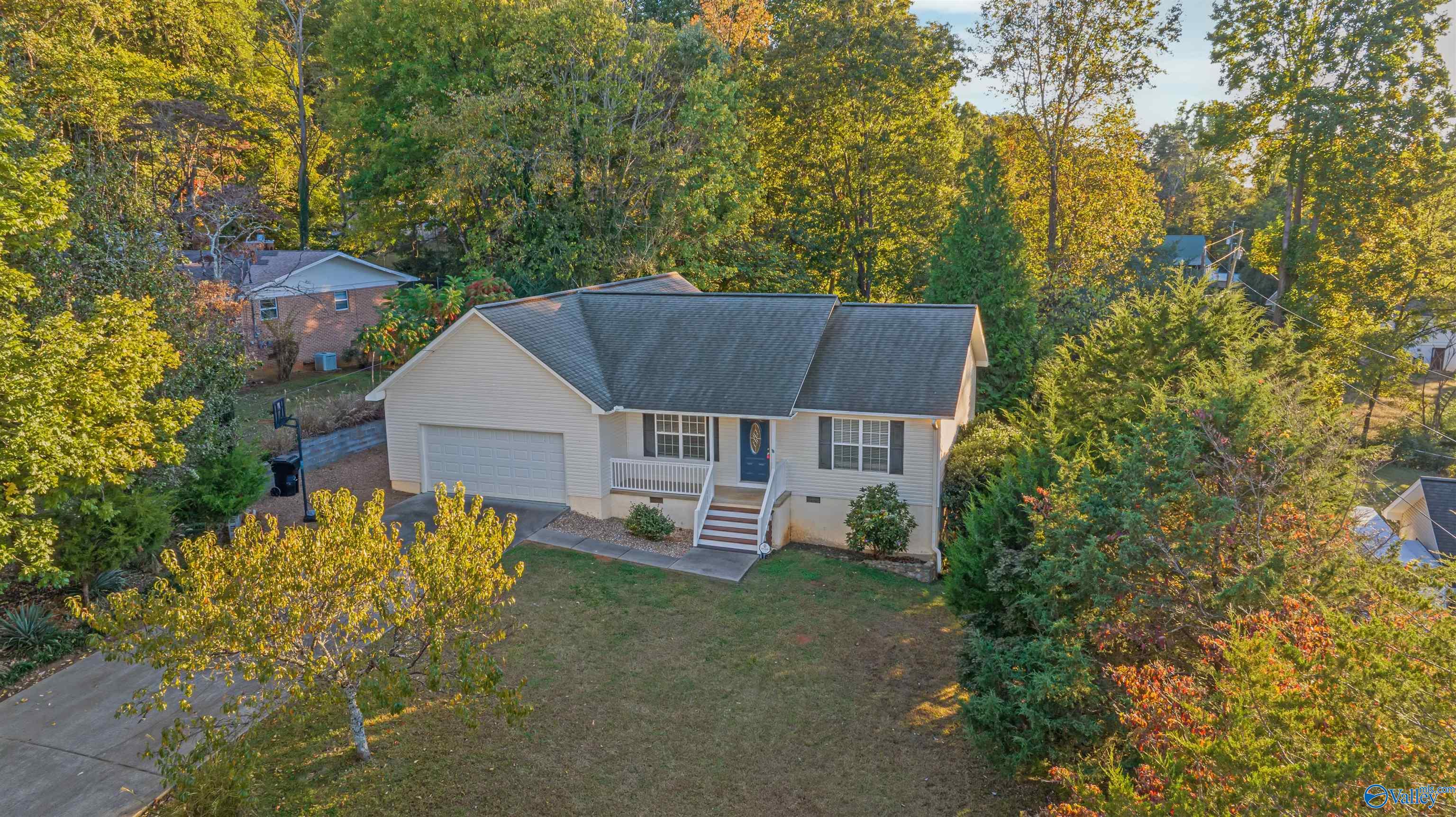 Single-story home with an attached garage and front porch, surrounded by autumn trees.
