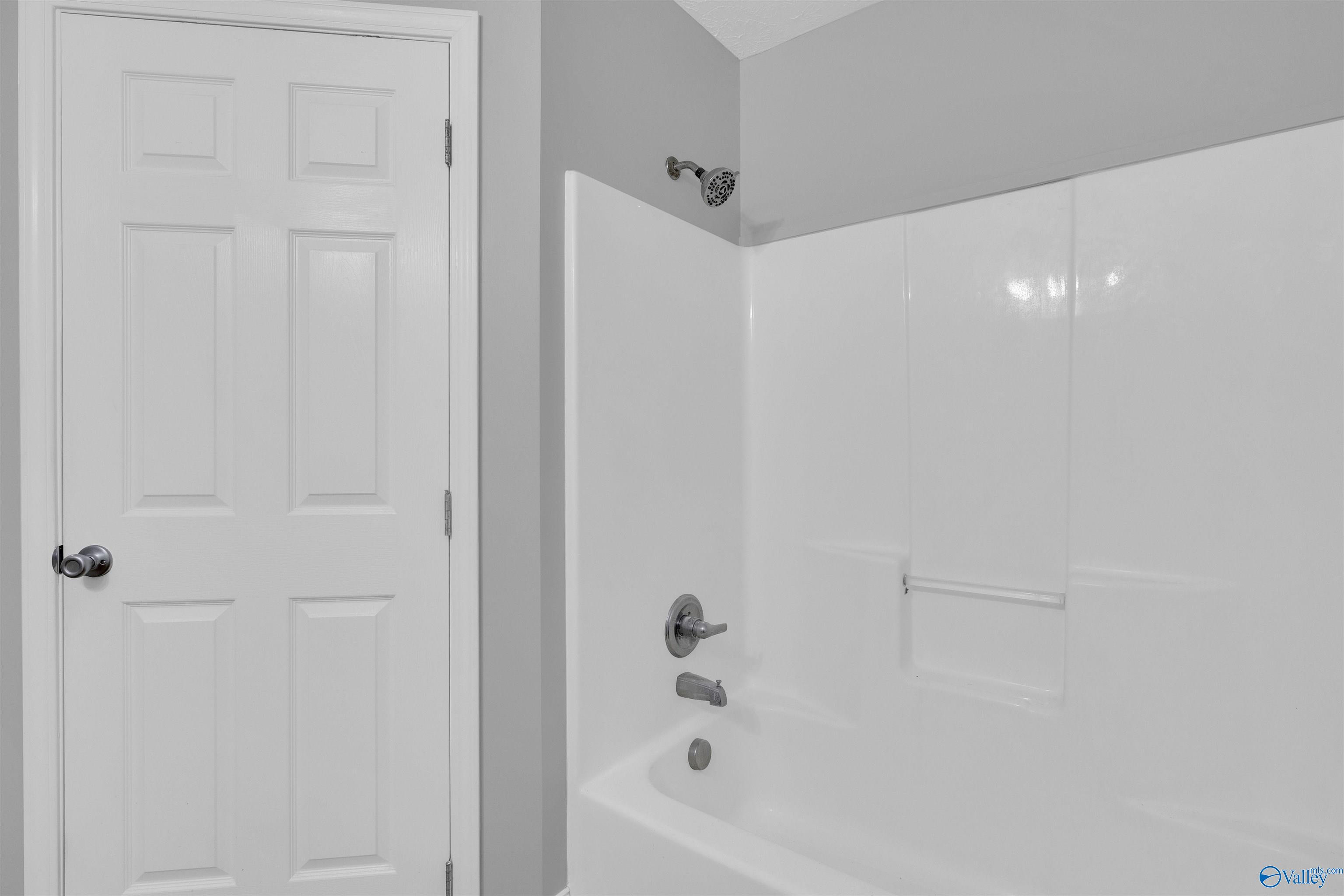 Bathroom tub and shower with a molded white surround and chrome fixtures.