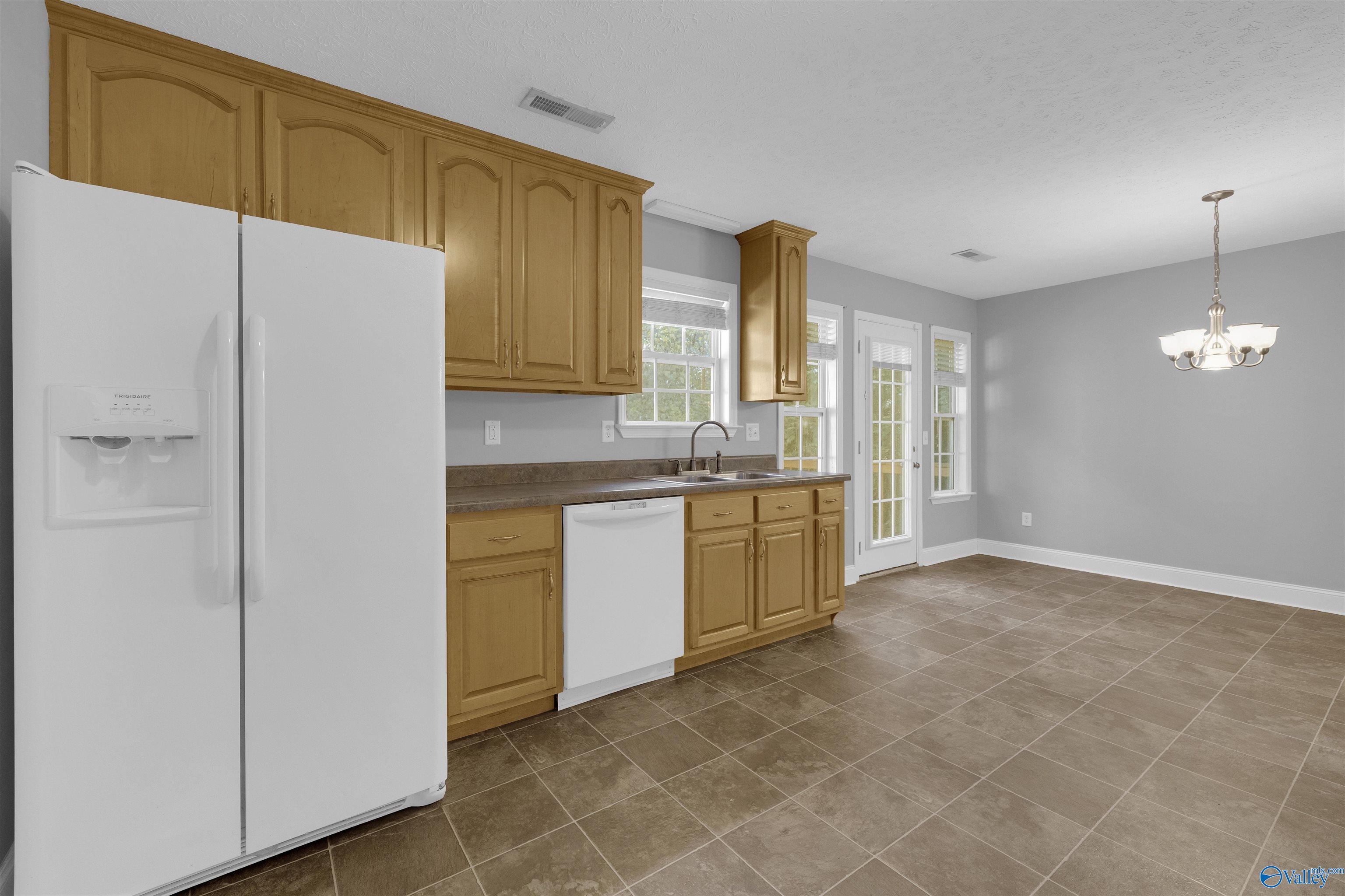 Kitchen with honey-colored cabinets, brown tile floors, and a glass-paneled exterior door.