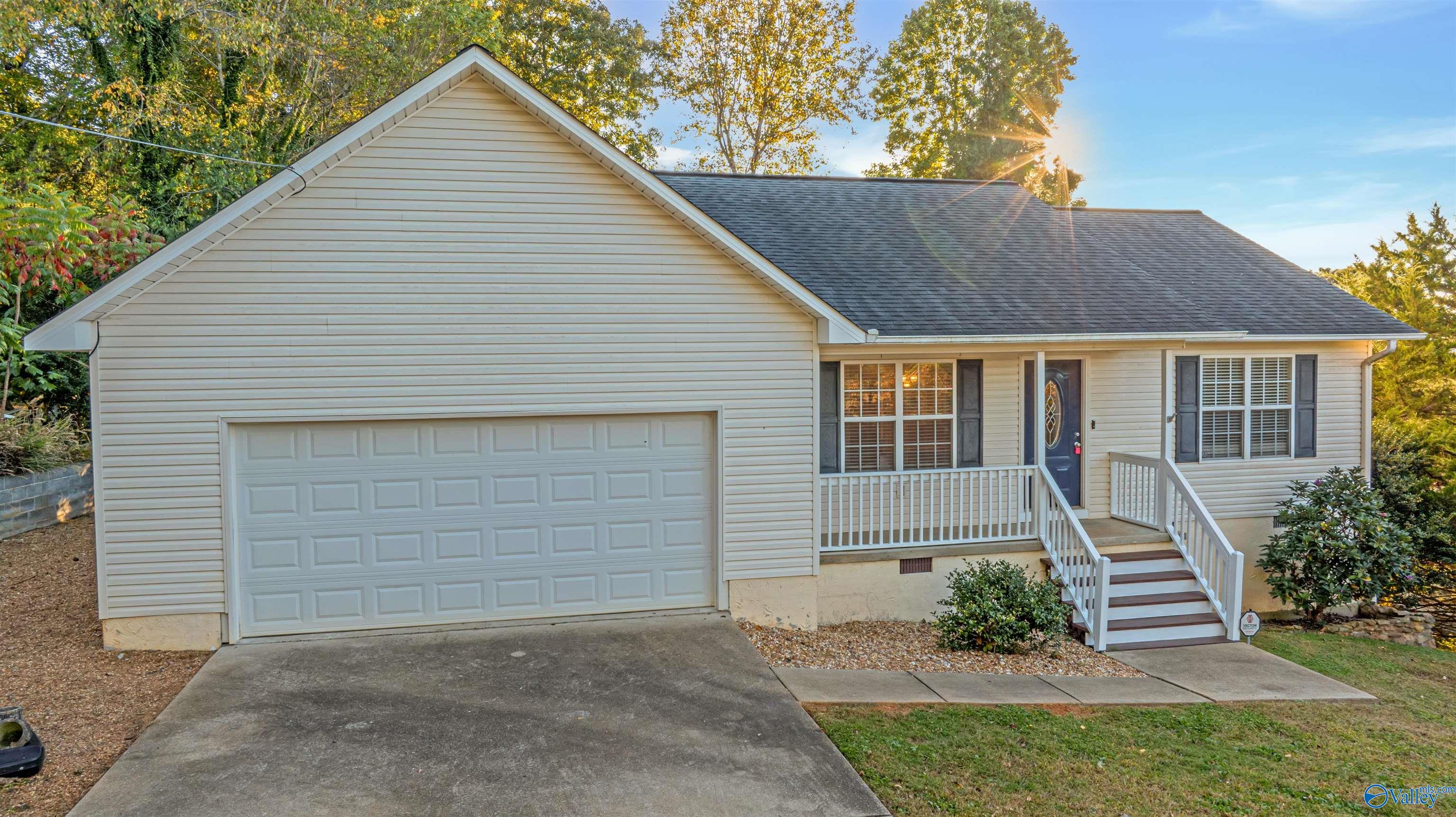 House exterior with an attached two-car garage, raised front porch, and white-railed steps.