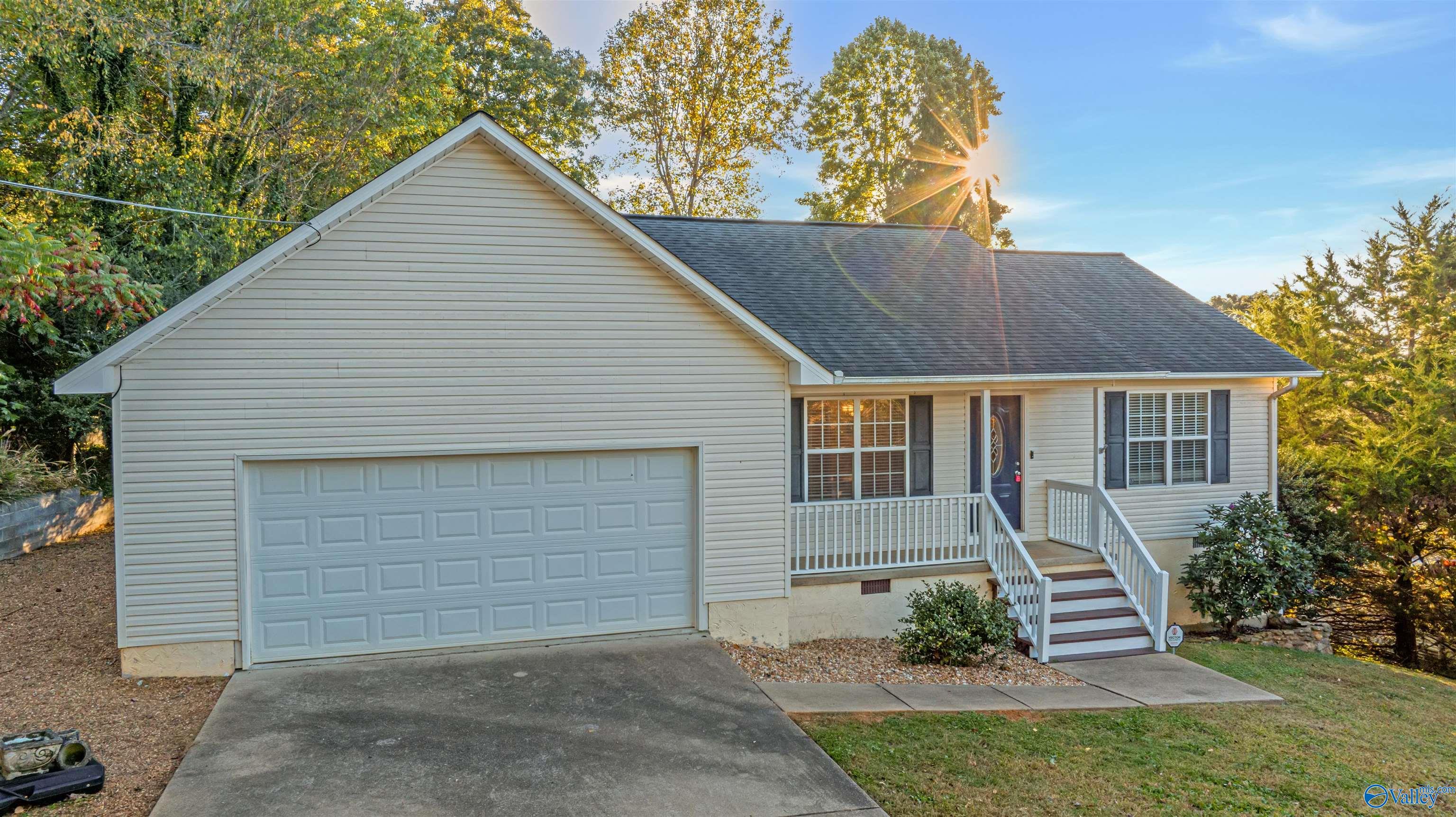 House exterior with a large garage and railed front steps, framed by autumn trees in golden sunlight.