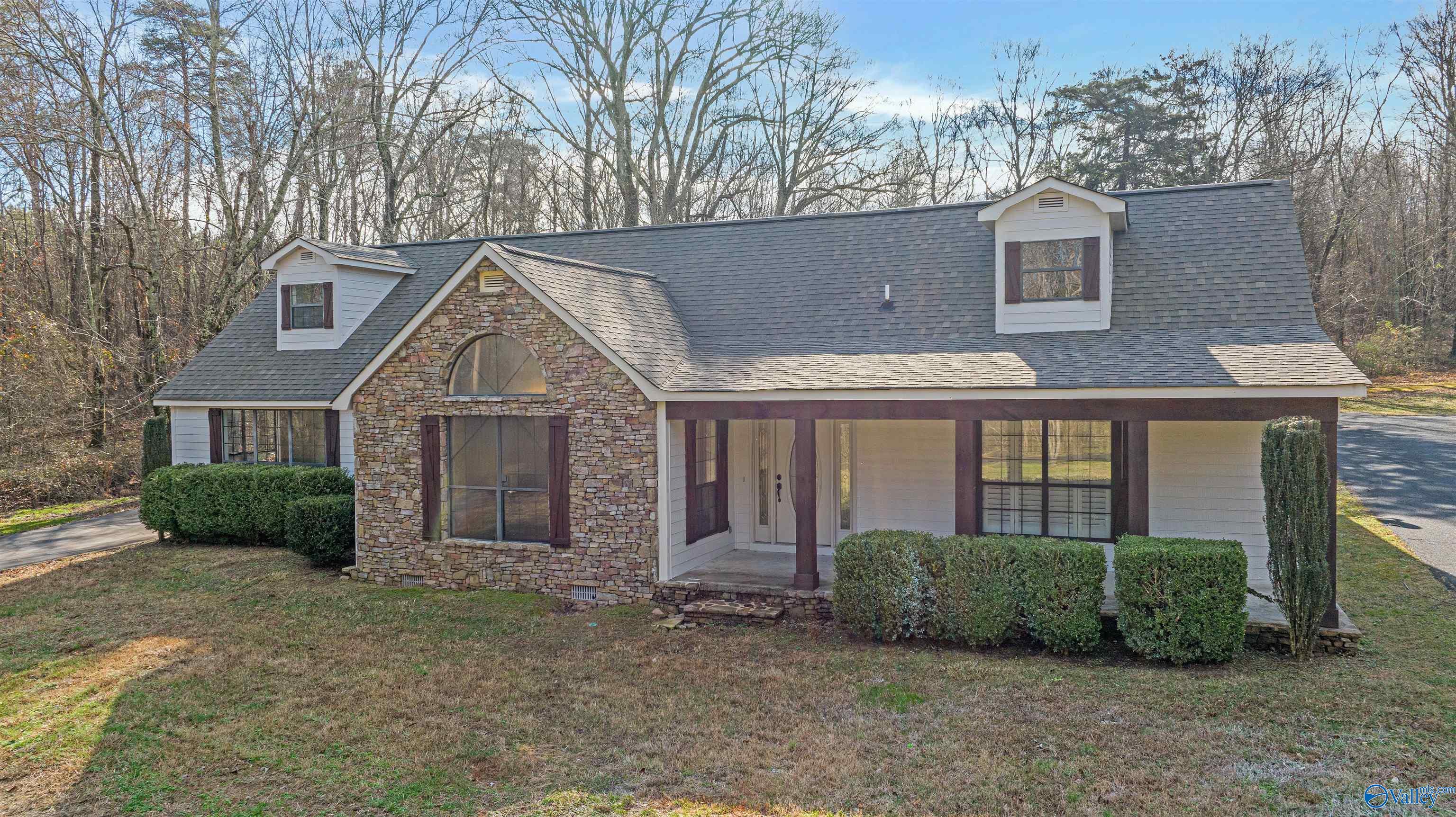 House with a stone-faced front gable, two roof dormers, and a covered porch.