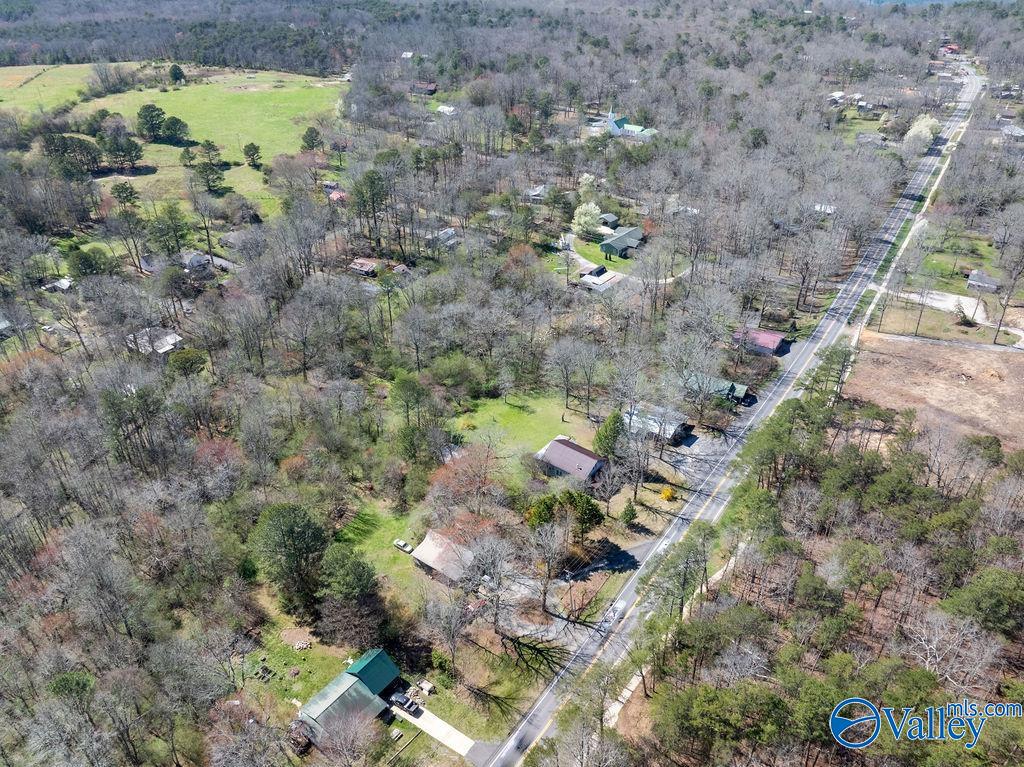 Aerial view of wooded homesites and scattered houses along a rural highway.