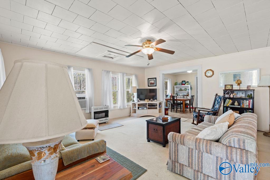 Living room with a ceiling fan, large windows, and an open dining area.