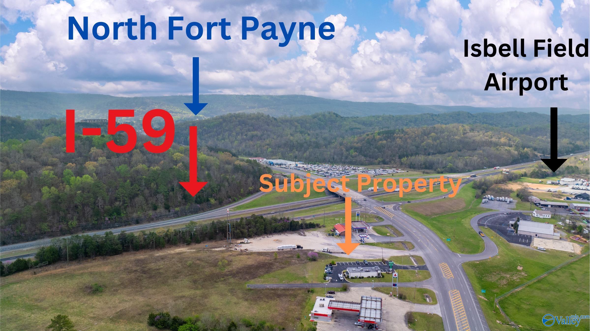 Aerial view of the marked property beside a highway interchange, with wooded hills and nearby commercial buildings.