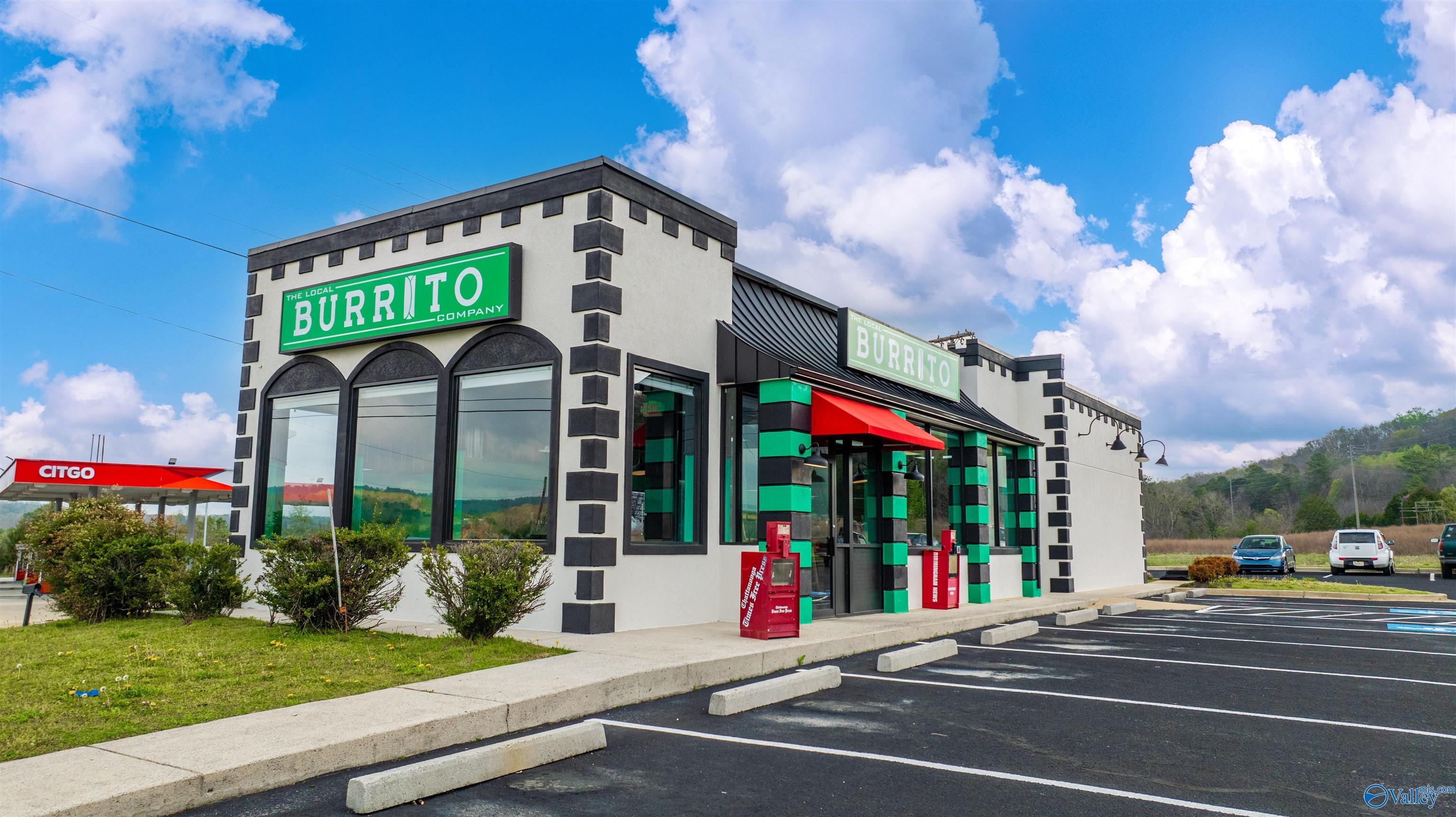 The Local Burrito Company restaurant with green-and-black trim, red awnings, and a mostly empty parking lot.