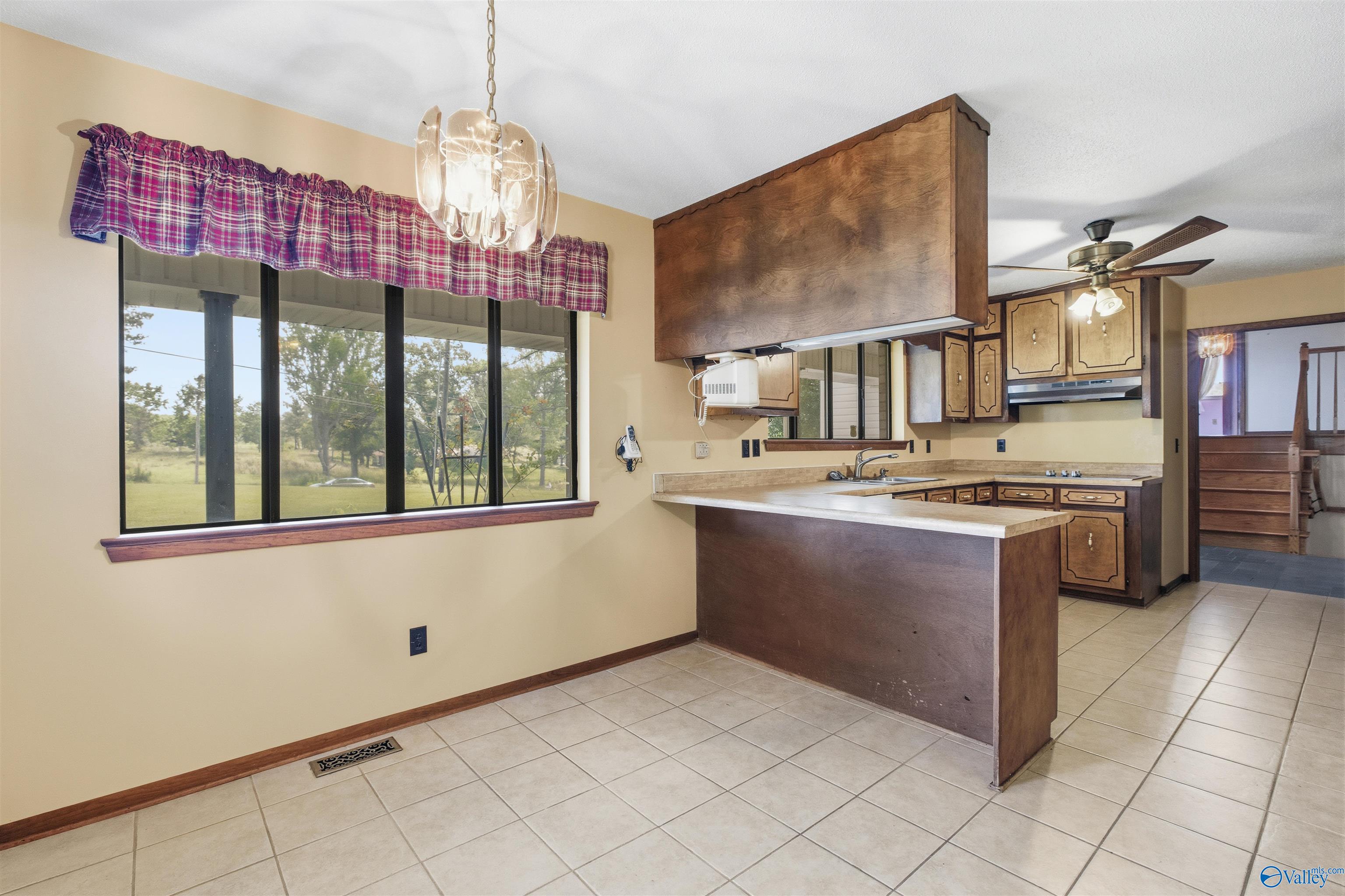 Kitchen with dark wood cabinetry, a peninsula counter, and a large window overlooking the yard.
