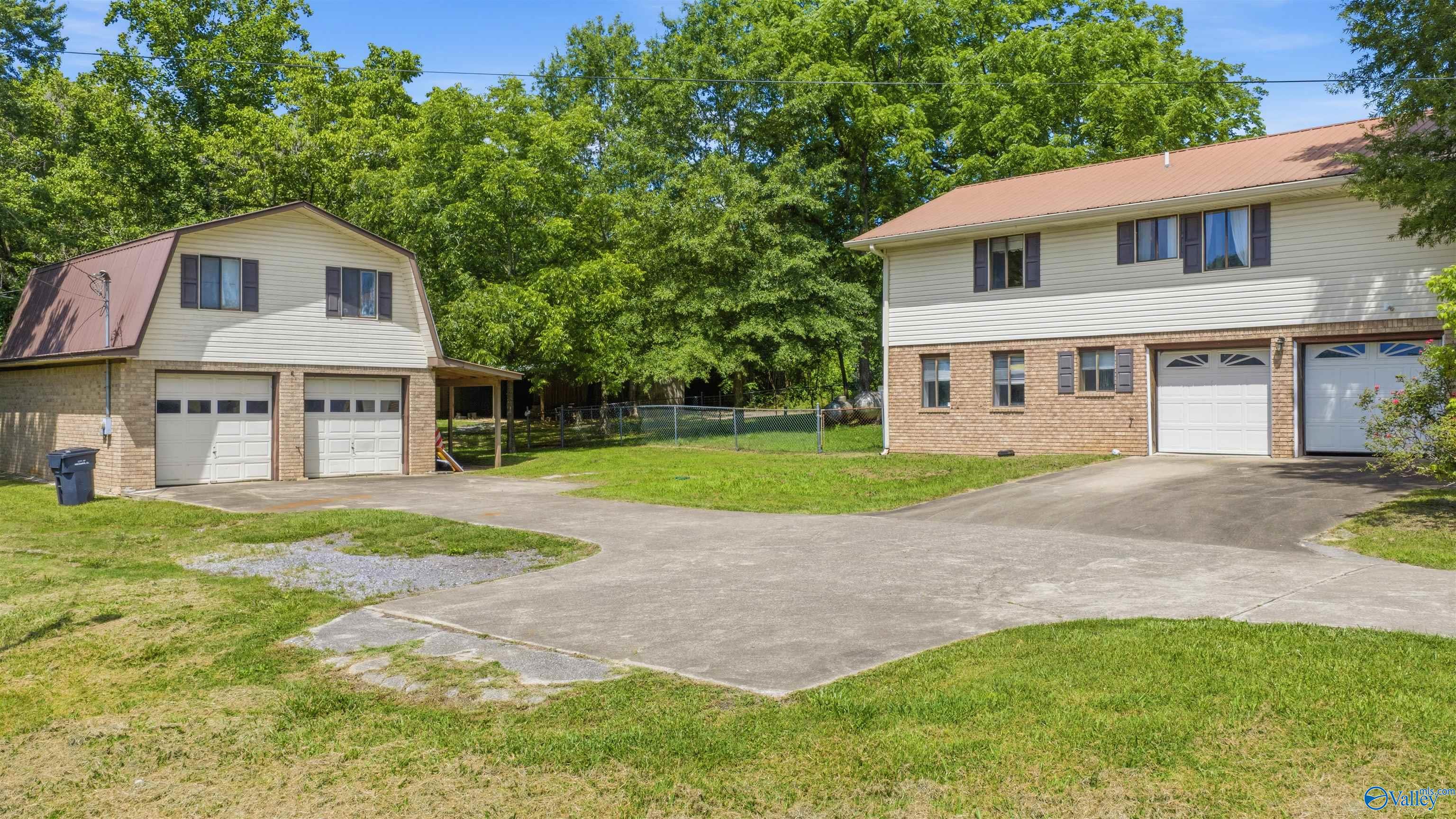 Two garage buildings with brick lower walls, pale siding, and a wide paved driveway.