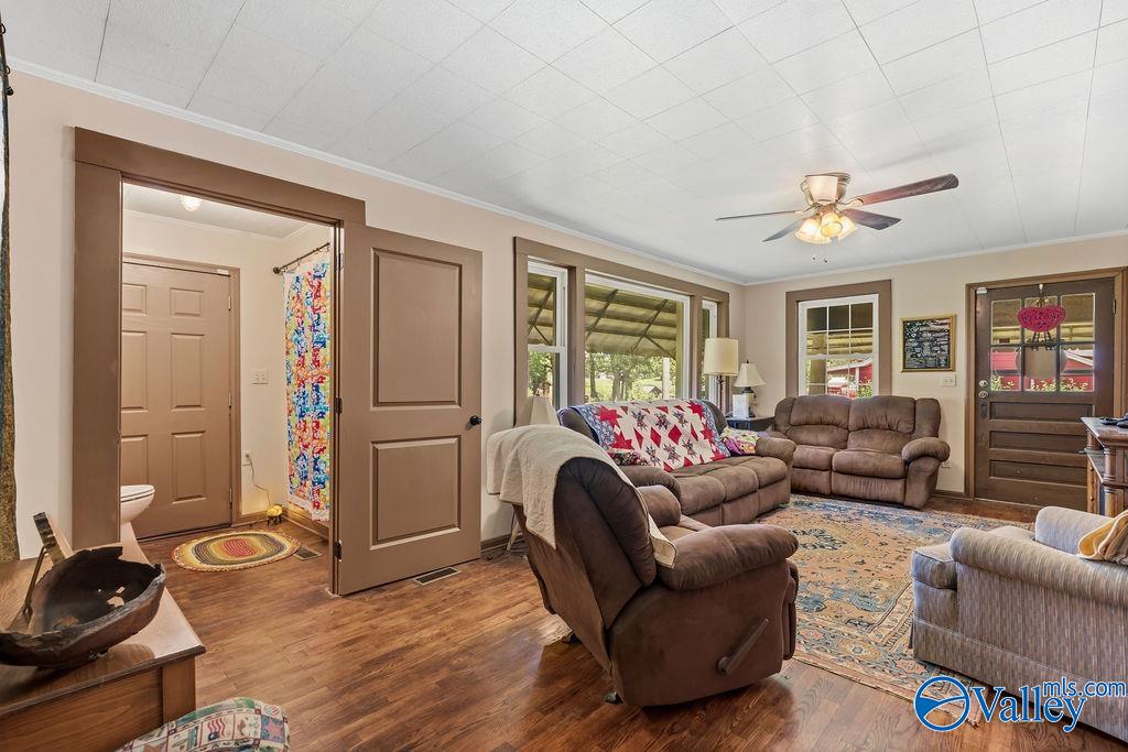 Furnished living room with brown recliners, a patterned rug, and windows facing a covered porch.