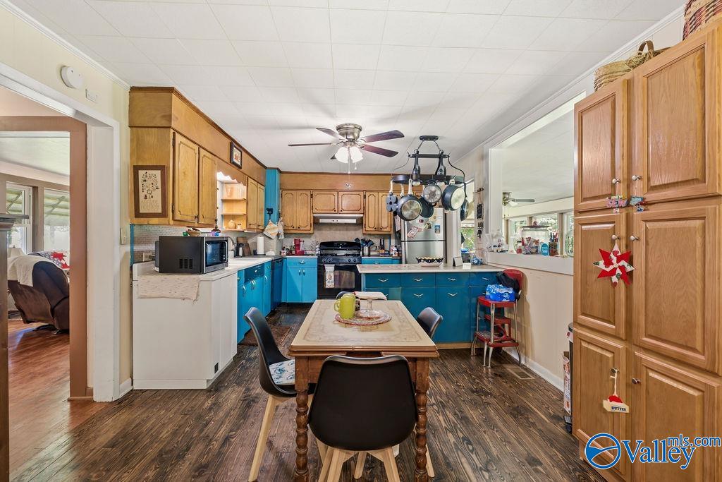 Kitchen with bright blue lower cabinets, wood cabinetry, a dining table, and a hanging pot rack.