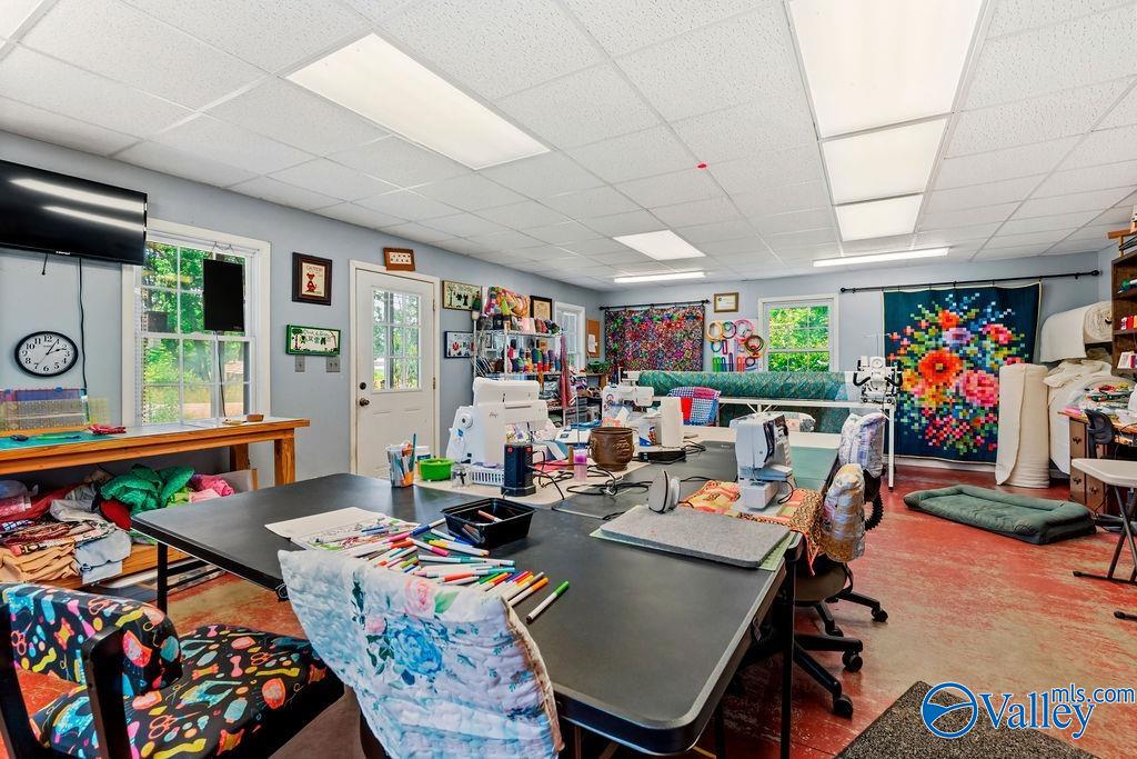 Craft room with sewing machines and worktables, colorful quilts, and fabric supplies.