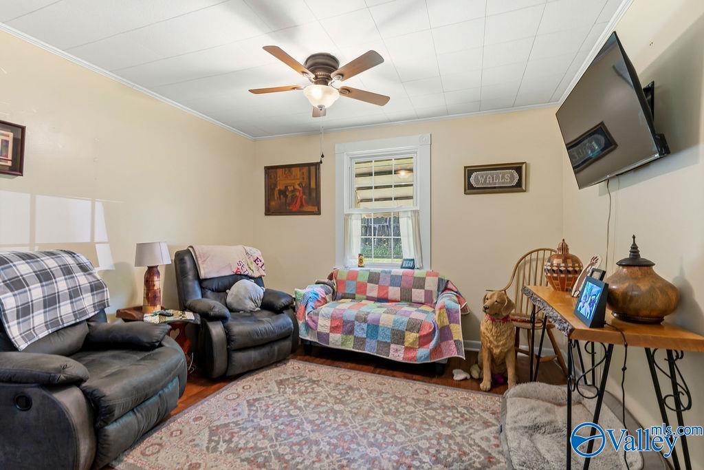 Furnished living room with leather recliners, a colorful patchwork loveseat, and a ceiling fan.