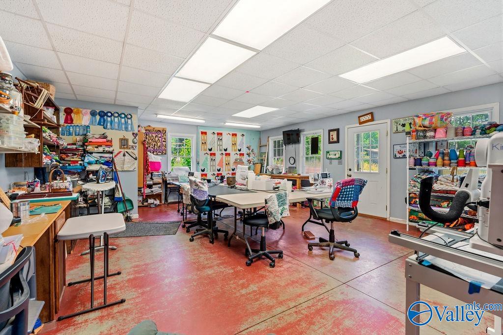 Sewing and craft room with worktables, sewing machines, and shelves of colorful fabric and thread.