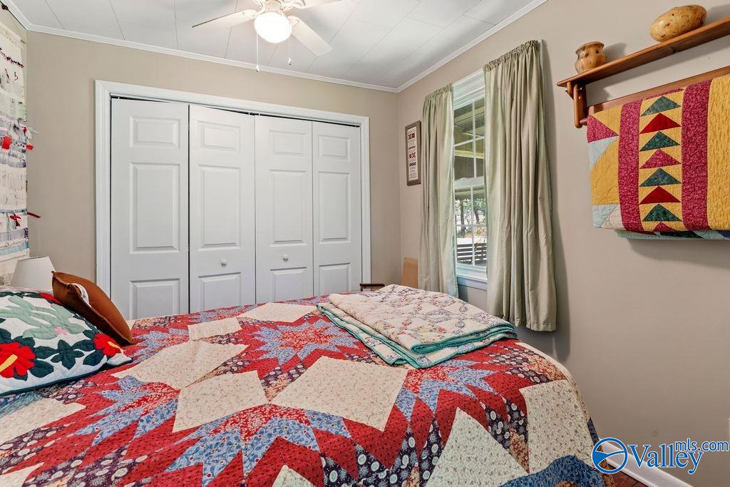 Bedroom with a red, blue, and cream patchwork quilt and white folding closet doors.