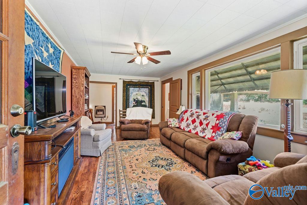 Furnished living room with brown reclining sofas, a patterned rug, and large windows overlooking a covered porch.